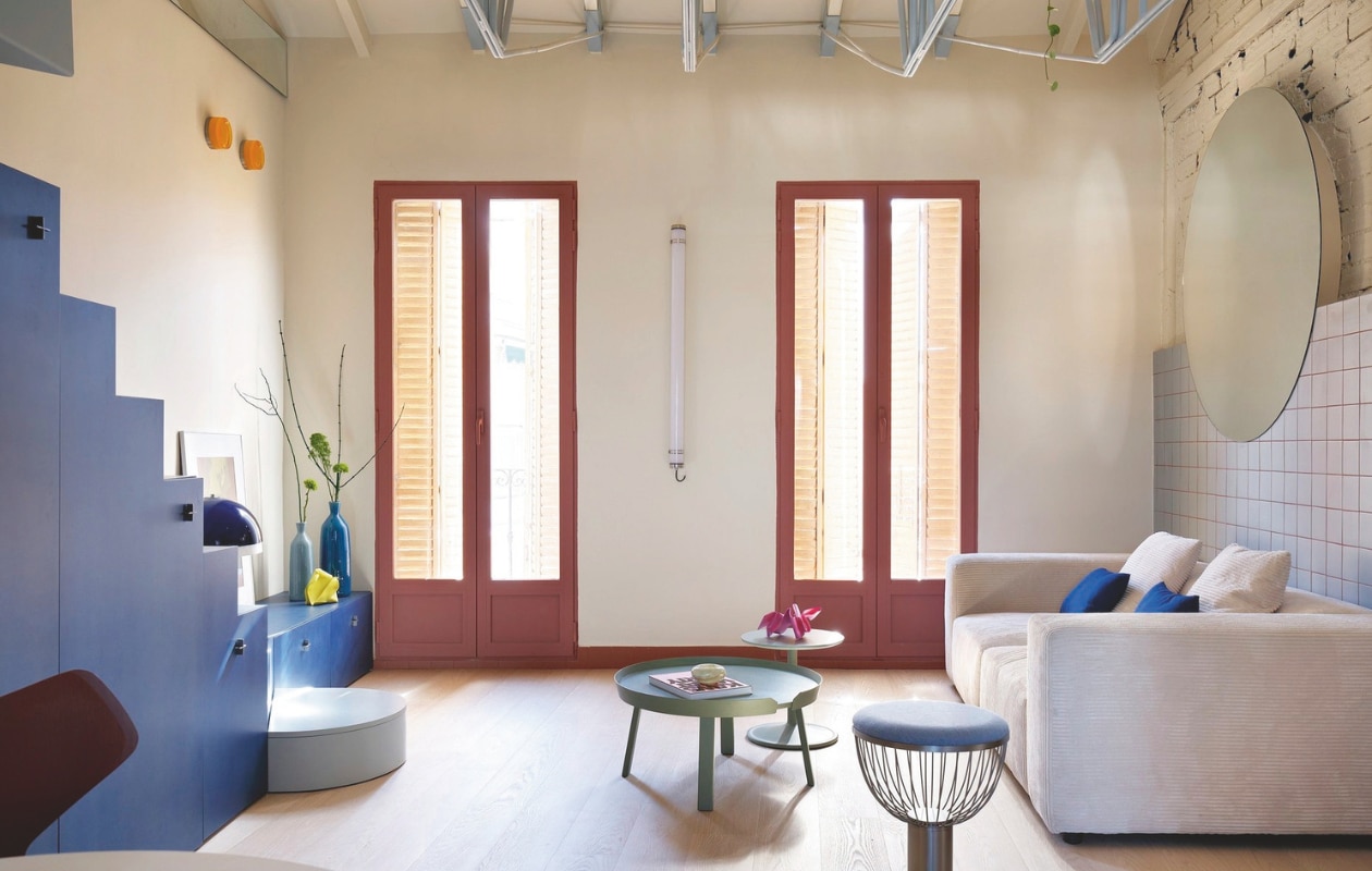 Oranje wandlampen Ginger van Marset. Tussen de ramen wandlamp van Faro Barcelona. Op het trapmeubel een vintage lamp en sculpturen van Iria Martínez. vtwonen 01-2026 | fotografie Germán Sáiz