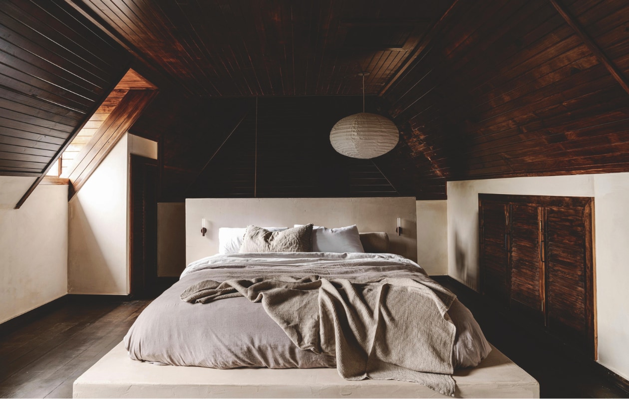 Het bedplatform is door Fred bekleed met microcement en versterkt het ‘geaarde gevoel’ in de slaapkamer. Achter het hoofdeinde is opberg- en hangruimte voor kleding. Soortgelijk: bollamp Paper Shade van Hay, wandlamp Claremont van Corston, beddengoed Linot van La Redoute. vtwonen Landelijk 01-2026 | styling Belle Hemming | fotografie Marnie Hawson