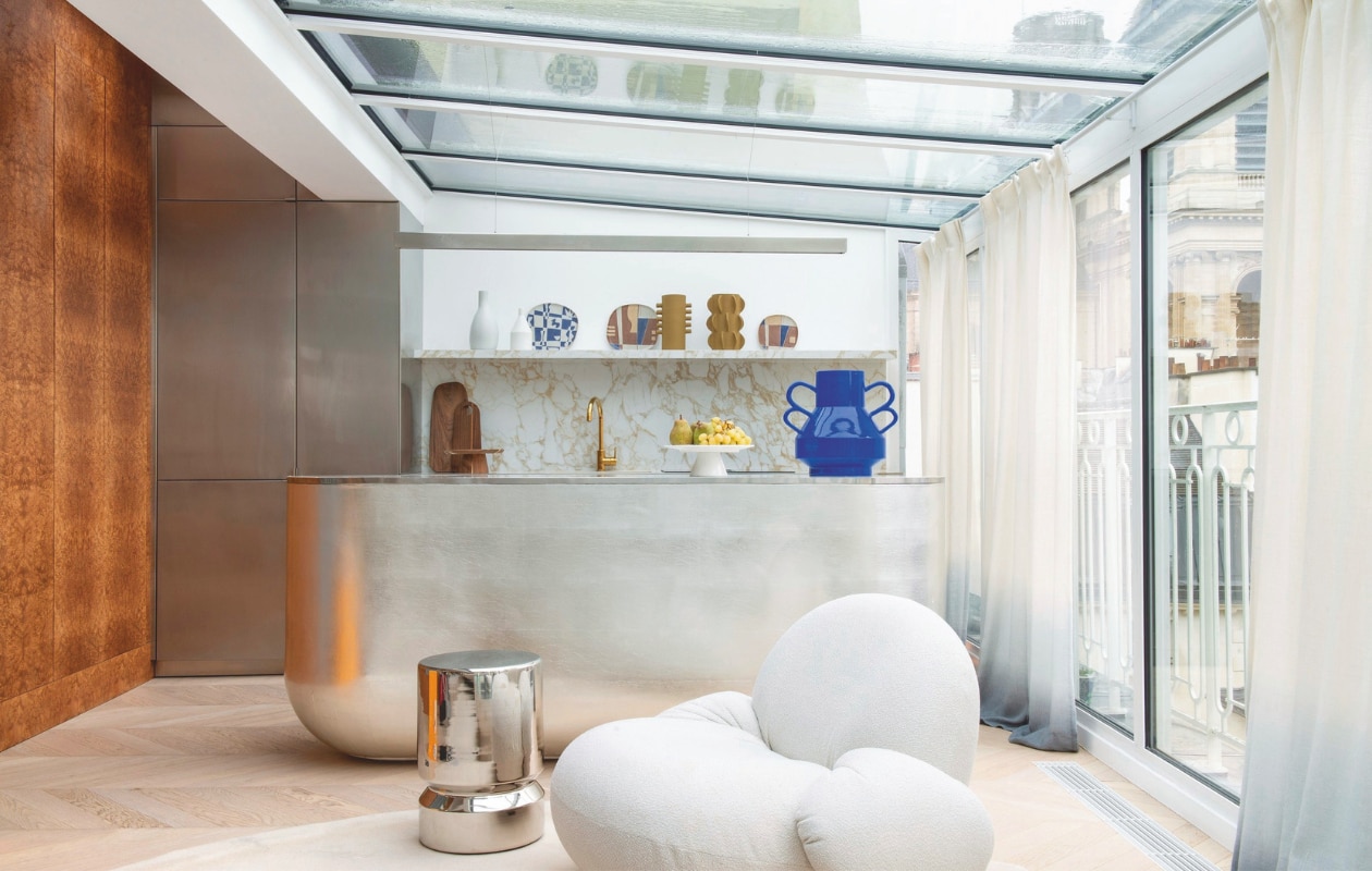 Blauwe vaas Margaux Keller x Monoprix. Borden Garance Vallée x Monoprix. Keramieken vazen Clay212. Snijplanken Monoprix. Visgraatparket Chatel van La Parqueterie Nouvelle. Wortelesdoornhouten fronten ontworpen door Amélie Vermersch. Fauteuil Pacha van Gubi. Gordijnen Ido Diffusion. vtwonen Design 01-2026 | fotografie Nicolas Mathéus