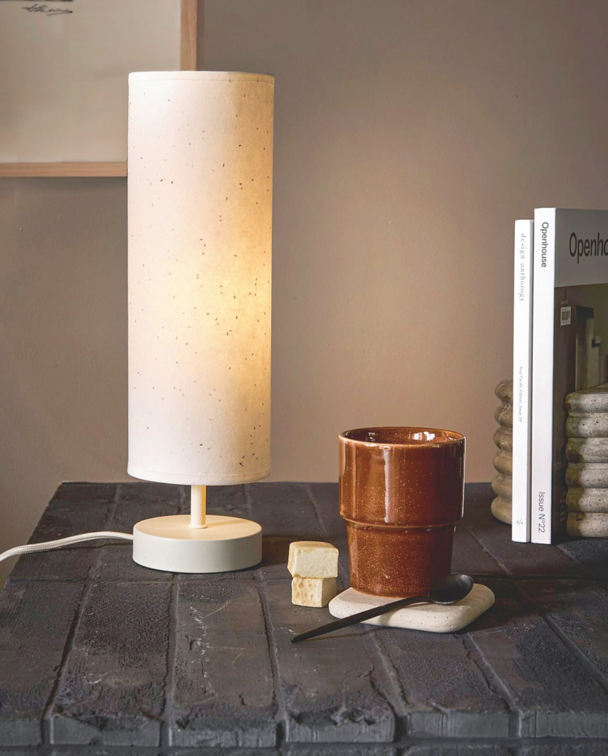 vtwonen tafellamp Paper Tube, papier, 11x36,5 cm (Øxh)€ 39,99.M.m.v. Loods5.nl (beker, artwork, boekensteunen). Overig privébezit. vtwonen 02-2026 | styling Marlies Does | fotografie Peggy Janssen