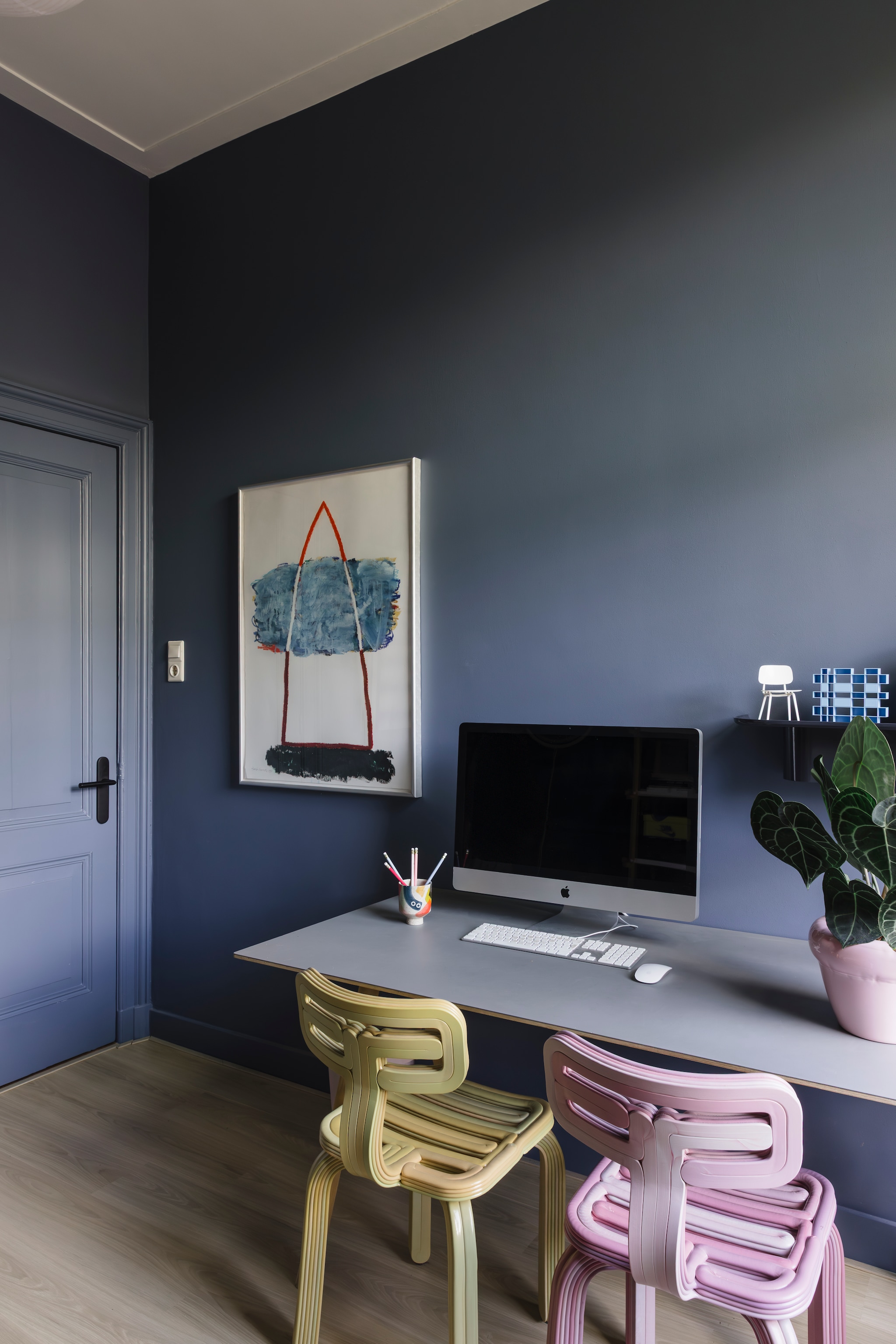 Muurkleur Juniper Ash van Little Greene. Stoelen Dirk van der Kooij. Tafel en wandplank Hay. Ministoel Revolt van Ahrend. Kunstwerk Harrie Gerritz. Beker Studio Arhoj. Roze pot Home Studyo. vtwonen 05-2026 | styling stylestek | fotografie Eva bloem