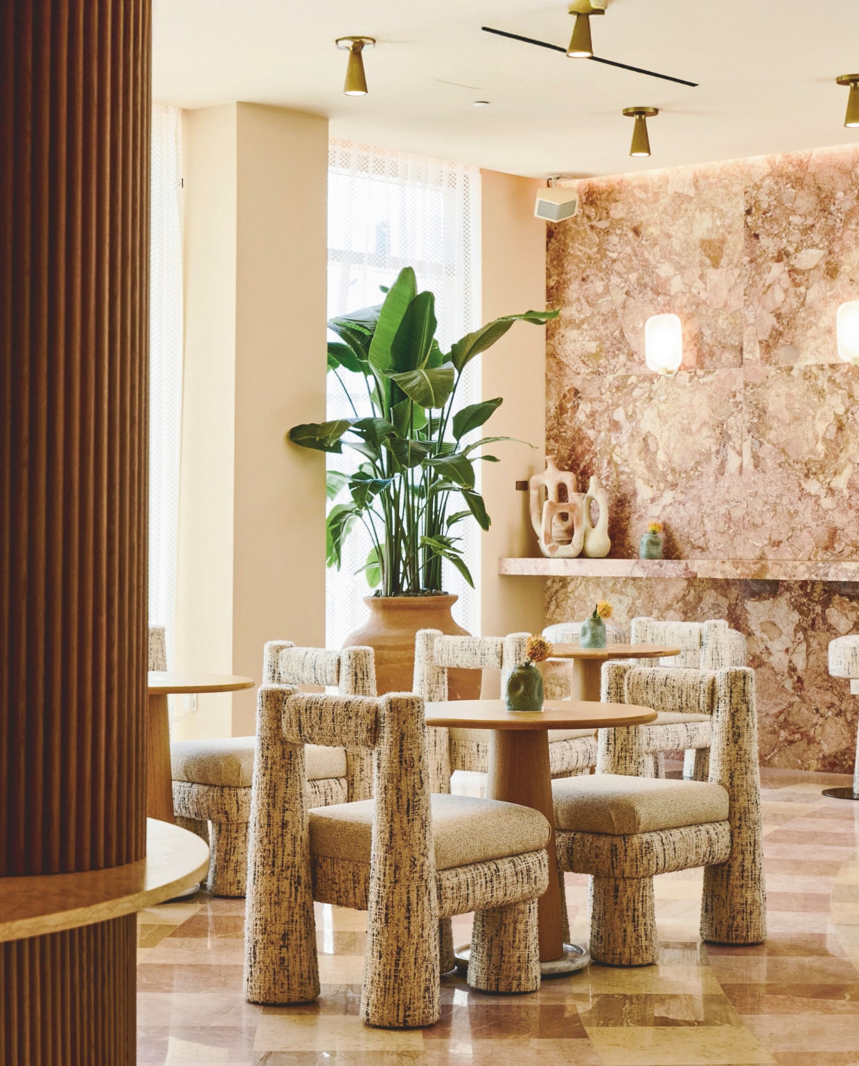 Plafondhoge ramen overspoelen de lobby met natuurlijk licht. Het interieur bevat onder meer marmeren bijzettafels van gerecyclede stenen uit een Spaanse steengroeve, vintage meubels uit Spanje en op maat gemaakte geweven tapijten uit Portugal. Wandkunst van Regina Jestrow. vtwonen Design 01-2026 | fotografie The Shelborne By Proper