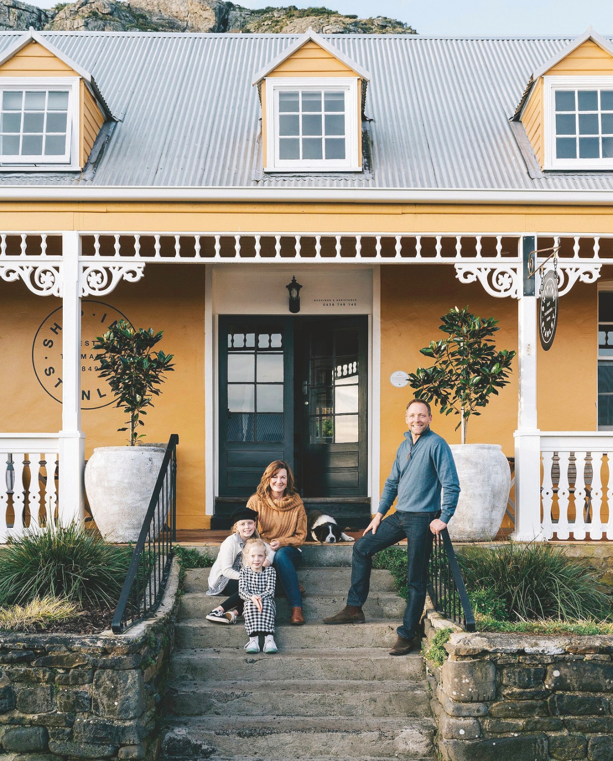 Kerry en Alastair met hun dochters Lucy en Bonnie. De mosterdkleurige verf is een op maat gemaakte mix. Lijstwerk geschilderd in Barely There van Haymes Paint. vtwonen Landelijk 02-2026 | styling Belle Hemming, Lynda Gardener | fotografie Marnie Hawson