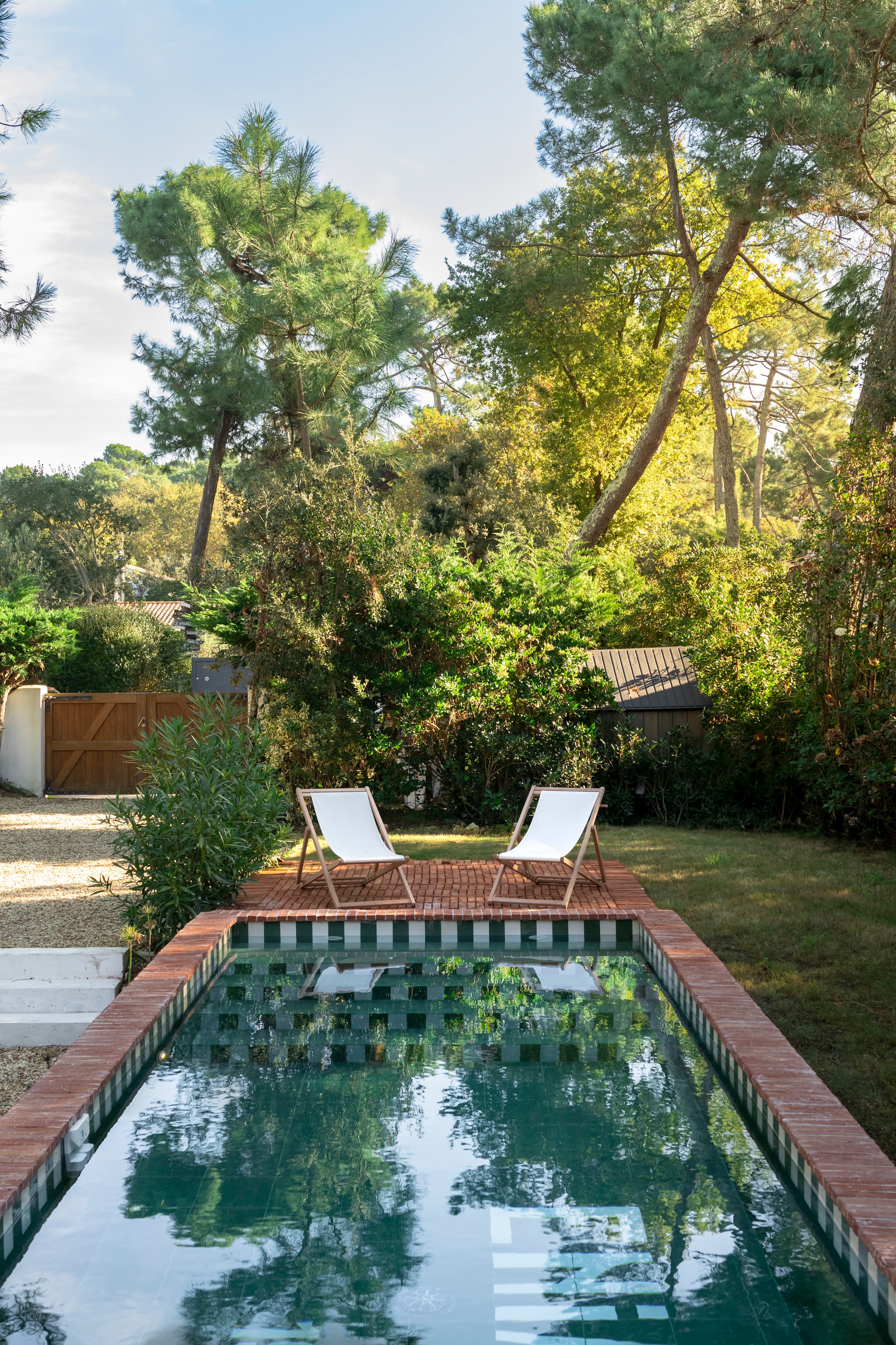 Op de bodem van het zwembad de bouw-datum en naam van het huis in letters identiek aan de originele typografie die ooit op de gevel was geschilderd. Ontwerp Theresa. Zwembad aangelegd door Infinity Pool. Ligstoelen Alinéa. vtwonen landelijk 7-2026 | styling Amandine Berthon | fotografie Julien Fernandez | productie Amandine et Jules