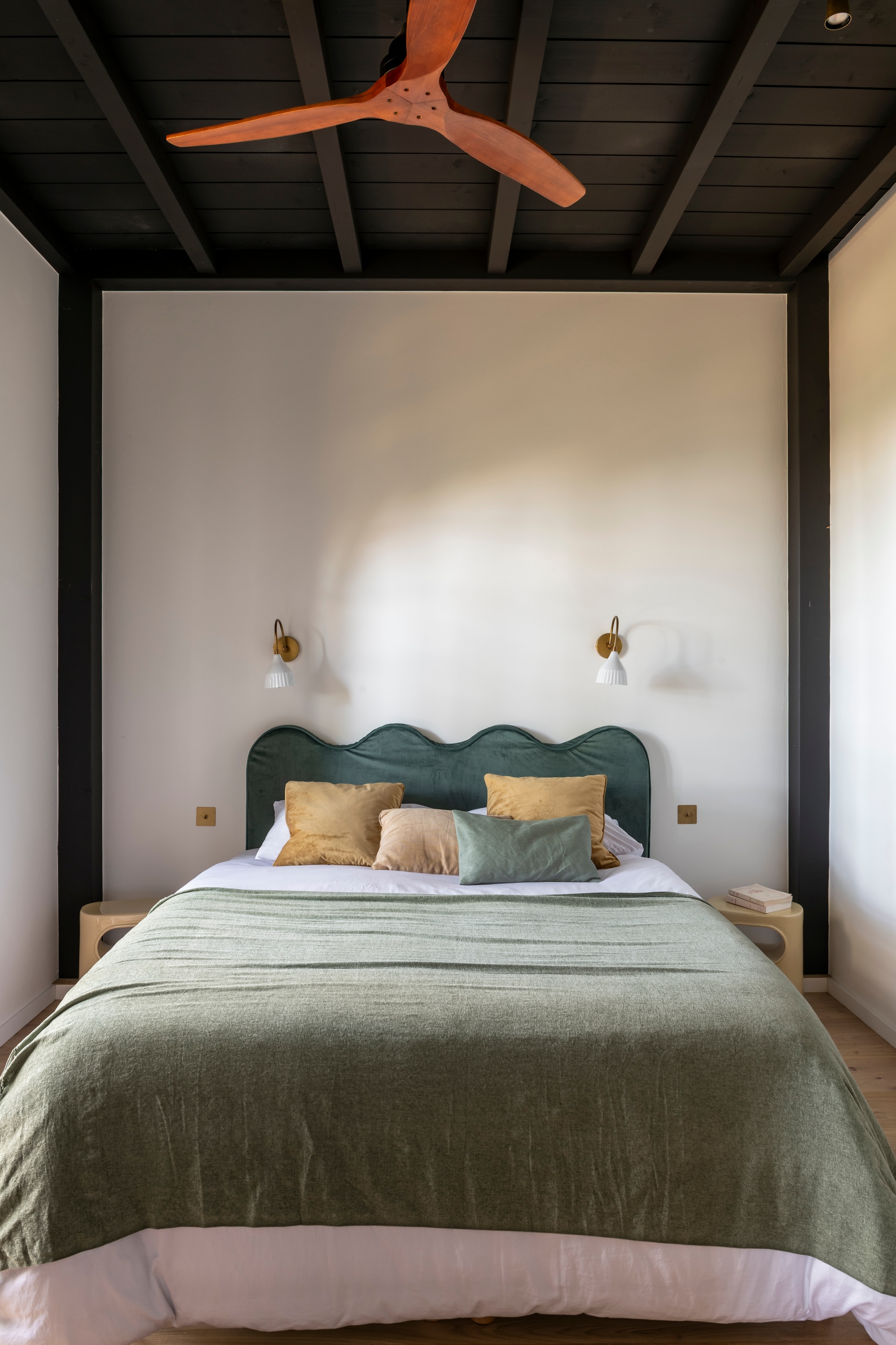 Fluwelen hoofdbord van bed in logeer-kamer, ontworpen door Theresa. Krukken als nachtkastjes HKliving. Beddengoed Linen Bundle. Plaid en kussens Zara Home. Vintage wandlampen tweedehands. Ventilator Create.  styling Amandine Berthon | fotografie Julien Fernandez | productie Amandine et Jules