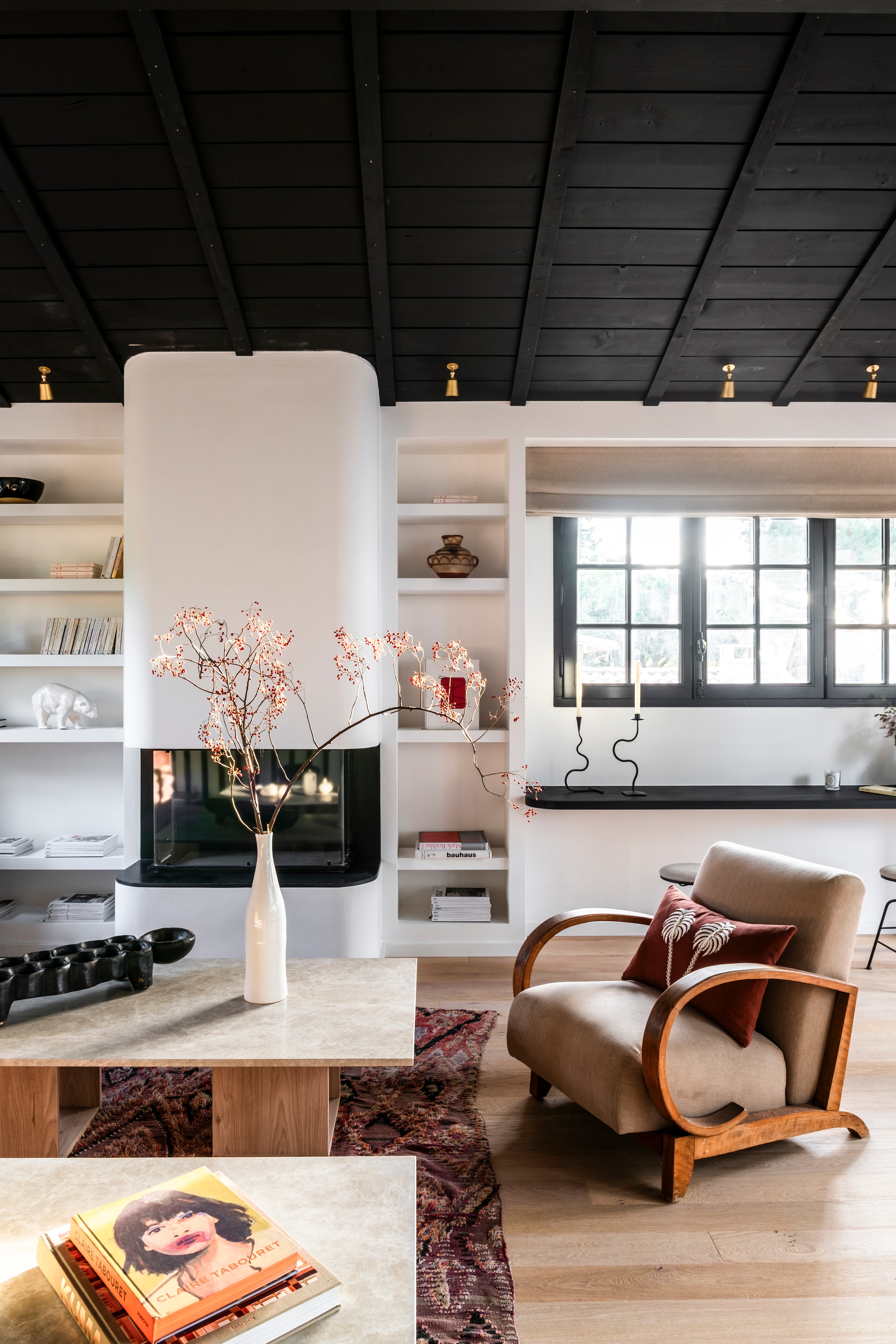 De zitkamer op de nieuwe verdieping. Boekenkast, open haard en salontafels ontworpen door Theresa. Fauteuil uit de jaren 30. Kussens La Casano. Spots Corston. Vaas Alinéa.