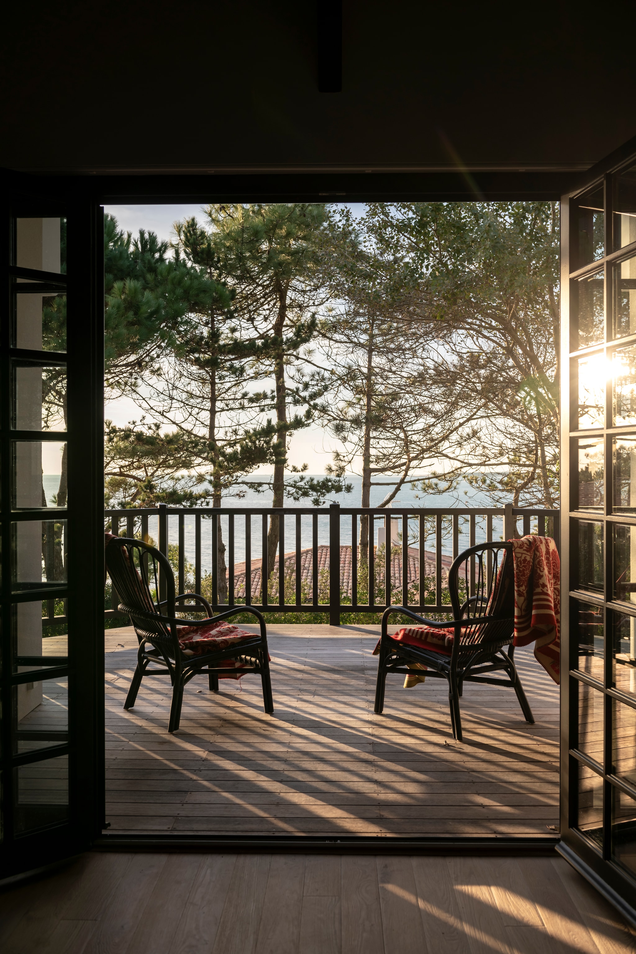 Het balkon van de bovenste verdieping is een uitkijkpost over de baai. Soortgelijke fauteuils The Cool Republic. Plaid Oleana. vtwonen landelijk 7-2026 | styling Amandine Berthon | fotografie Julien Fernandez | productie Amandine et Jules