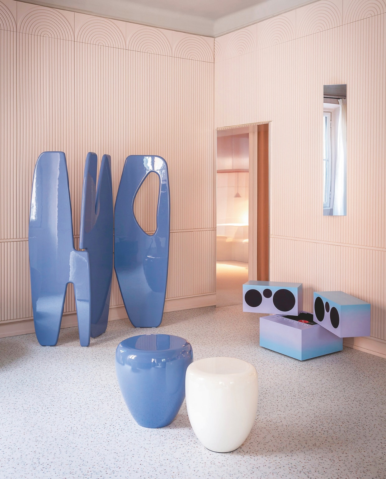 Gelakt kamerscherm Panama van Reda Amalou Design. Radio en platenspeler Totem RR231 van Brionvega. Spiegelende wandlamp Shard van Caroline Chao. Gelakte houten bijzettafels Dot van Reda Amalou Design. Vloer Taralay Impression Compact van Gerflor. 3D-wandbekleding Canelé Arstyl van Noël & Marquet. Gepolijst zinken omlijsting van Materica. vtwonen Design 01-2026 | styling Studiopepe | fotografie Filippo Ferrarese & Silvia Rivoltella