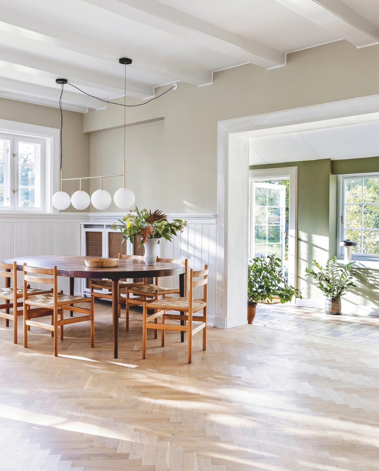 Eettafel Lauritz. Vintage stoelen van Kurt Østervig. Hanglamp Tr Bulb van Audo. Muurkleur tuinkamer Green Harmony van Jotun. vtwonen 02-2026 | styling Rikke Graff Juel | fotografie Christina Kayser O.