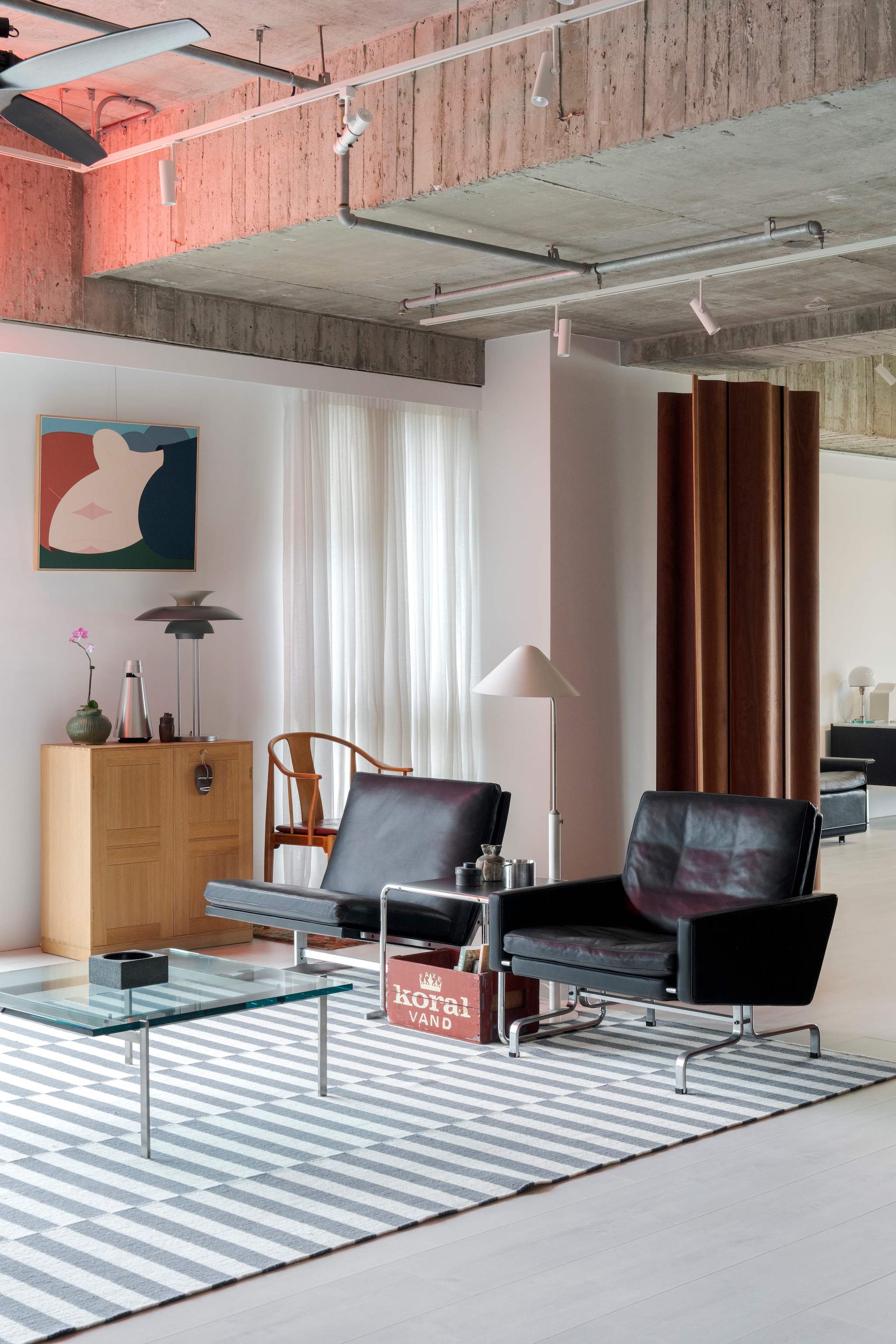 Fauteuil links Pk31 van Poul Kjærholm. Vloerlamp Vip van Jørgen Gammelgaard. Bijzettafel Laccio van Marcel Breuer. Fauteuil rechts Bo-561 van Fabricius & Kastholm. Kast Mogens Koch. Tafellamp Ph-5 van Poul Henningsen. Stoel China van Hans J. Wegner. Schilderij Heejo Lim. Vloerkleed Stockholm van Ikea.