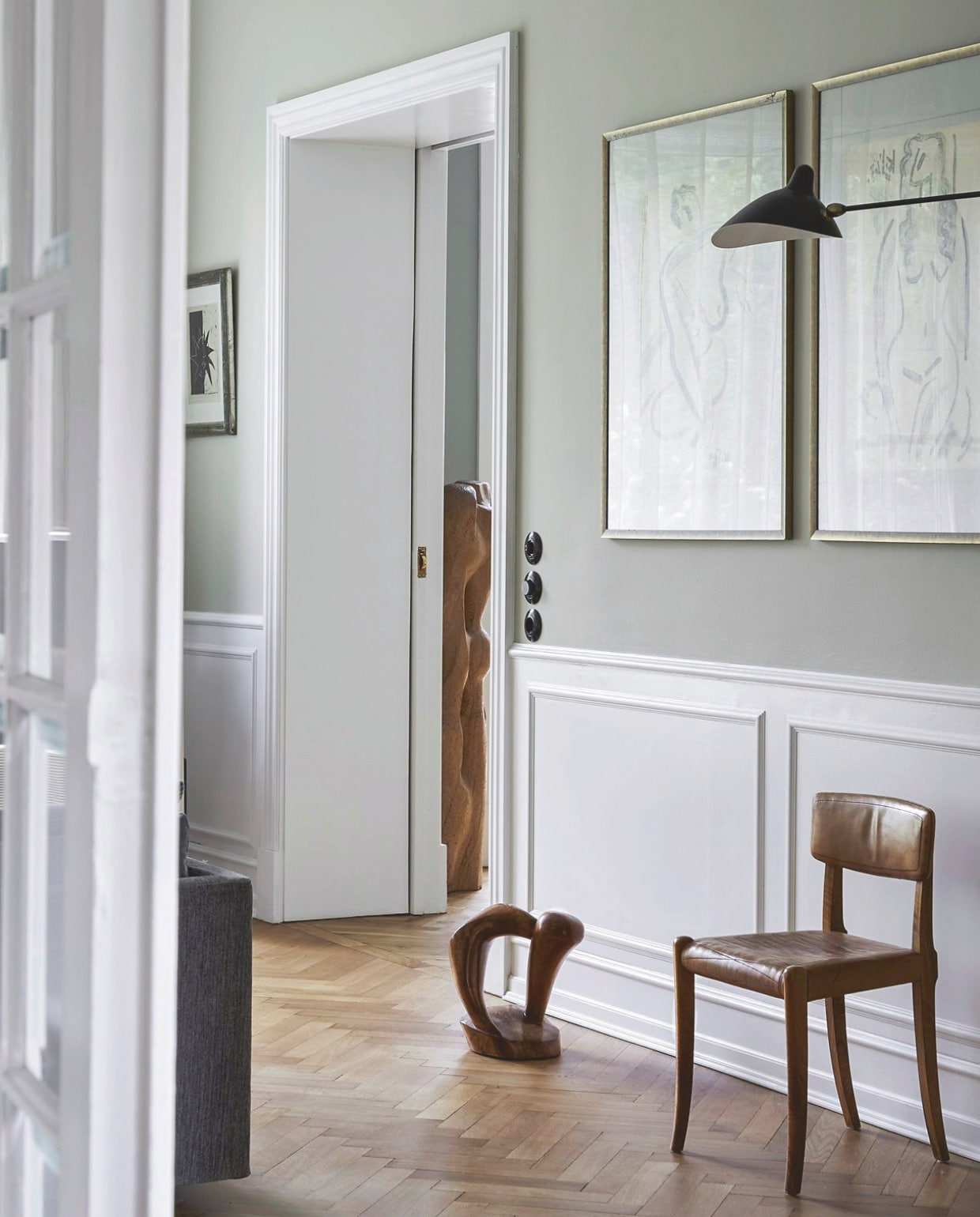 Wandlamp Applique van Serge Mouille. Lunstwerken Kjeld Jensen. Beeldhouwwerk in aangrenzende kamer Reinhold Wiwiorra. Houten sculptuur en stoel rommelmarkt. vtwonen landelijk 02-2026 | productie Living Inside | styling Marie Monrad Graunbol | fotografie Stine Christiansen