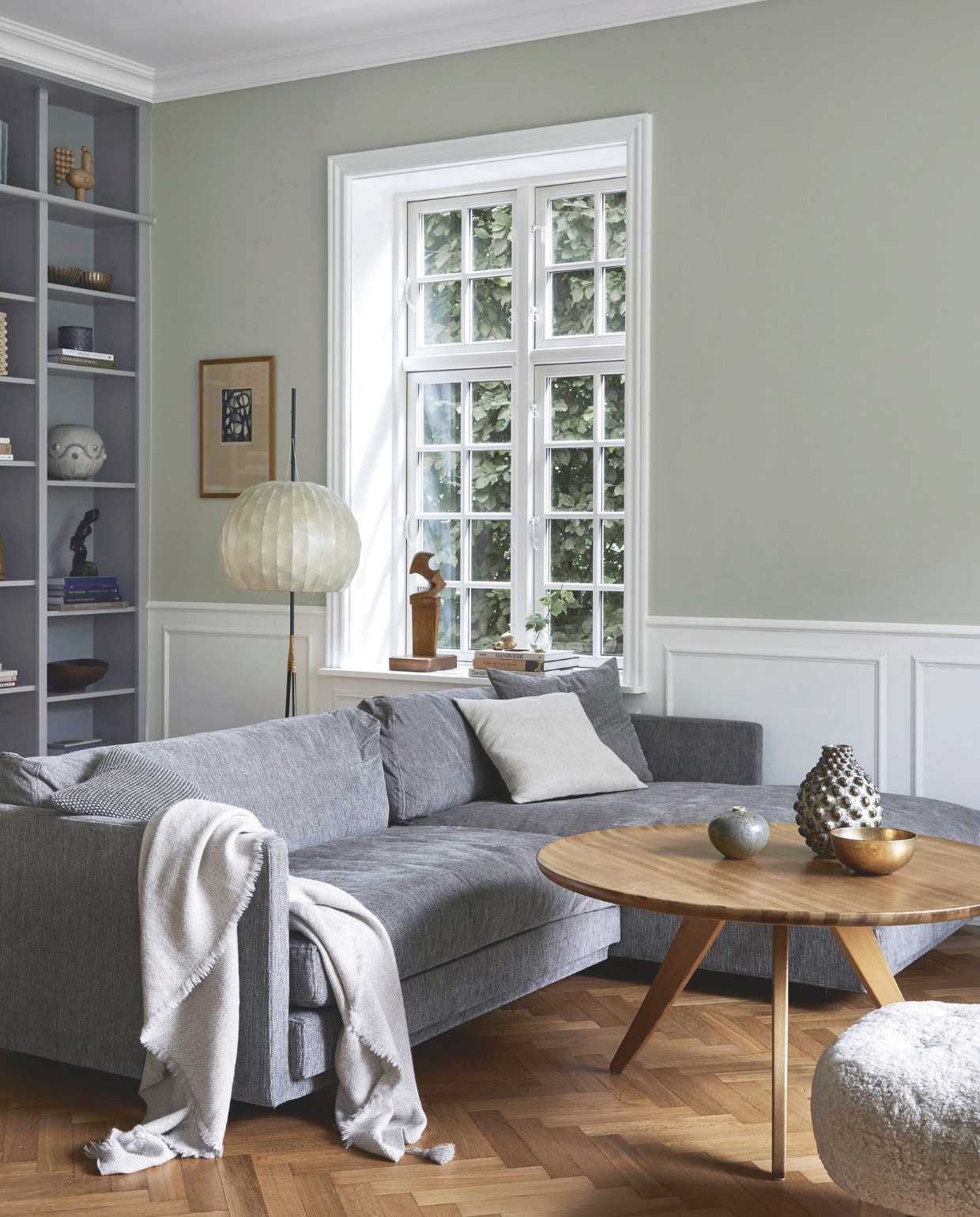 Bank Float van Eilersen. Vazen op tafel Axel Salto. Vintage staande lamp J.T. Kalmar. Vintage lithografie Modern Collect. Houten beeld rommelmarkt. Boekenkast maatwerk. Bolvaas Arno Malinowski. Houten sculptuur Erik Thommesen. vtwonen landelijk 02-2026 | productie Living Inside | styling Marie Monrad Graunbol | fotografie Stine Christiansen