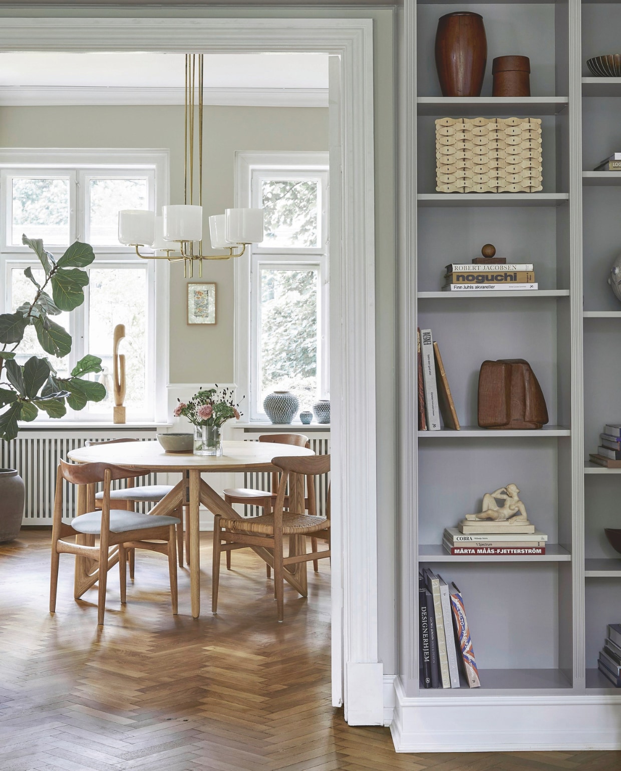 Eettafel Niels Koefoed via veiling Bruun Rasmussen. Stoel rechts Pp505 van Hans Wegner. Stoel links vintage Knud Færch. Kroonluchter via het Zweedse veilinghuis Bukowski. Beeld op vensterbank rommelmarkt. Aardewerk van Saxbo, Arne Bang, Eva Stæhr-Nielsen en Gunnar Nylund. vtwonen landelijk 02-2026 | productie Living Inside | styling Marie Monrad Graunbol | fotografie Stine Christiansen
