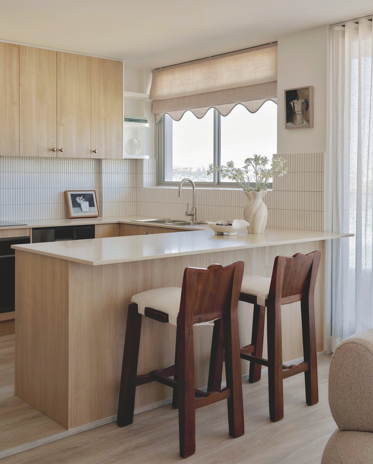 De keuken kreeg een upgrade met nieuwe fronten en een golvend afgewerkt rolgordijn. Barkrukken Clo Studios. Vaas Michelle Samaras. Schaal Tee McManus. vtwonen Design 01-2026 | fotografie Nic Gossage