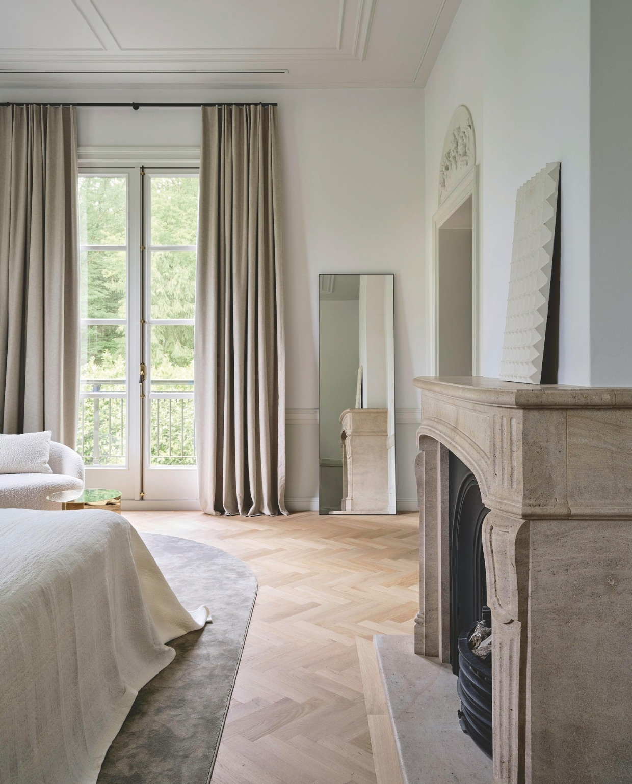 Het tapijt is op maat gemaakt en heeft een ronde zijde die correspondeert met de vorm van de haard en decoratie boven de deur naar de kleedkamer. Kunstwerk op schouw Galerie Oode. Spiegel Kasstoor. vtwonen 01-2026 | fotografie Space Content Studio