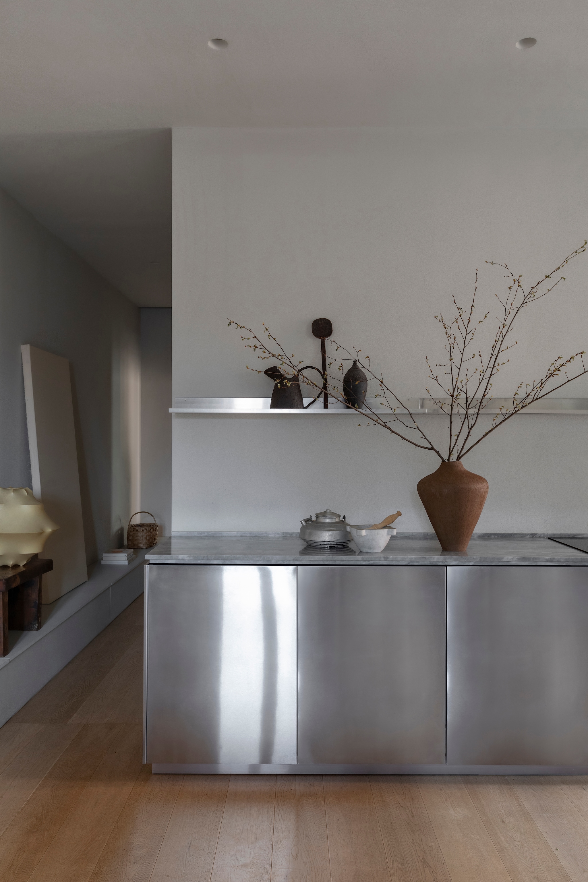 Vintage tafellamp Cocoon van Magazzino 76. De roestvrijstalen keuken is ontworpen door Moreno. Op het schap: karaf Elena Milani, houten lepel en vaas Milesi. vtwonen Design 04-2026 | styling Chiara Dal Canto | fotografie Helenio Barbetta | productie Living Inside