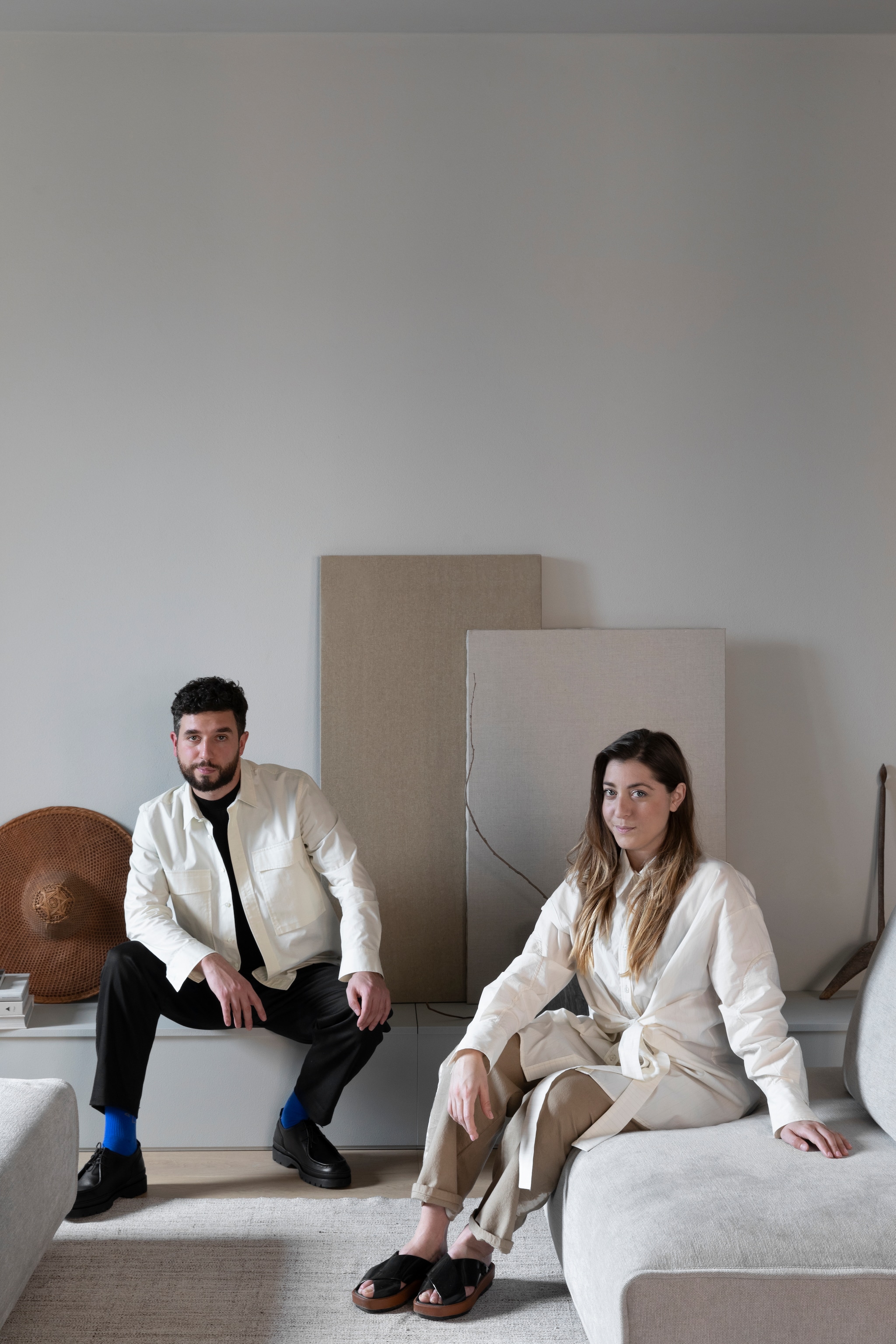 Moreno en Federica. Zij zit op haar eigen ontwerp, bank Niveaux voor Lema. Vloerkleed Altai. Rieten hoed uit Vietnam. vtwonen Design 04-2026 | styling Chiara Dal Canto | fotografie Helenio Barbetta | productie Living Inside