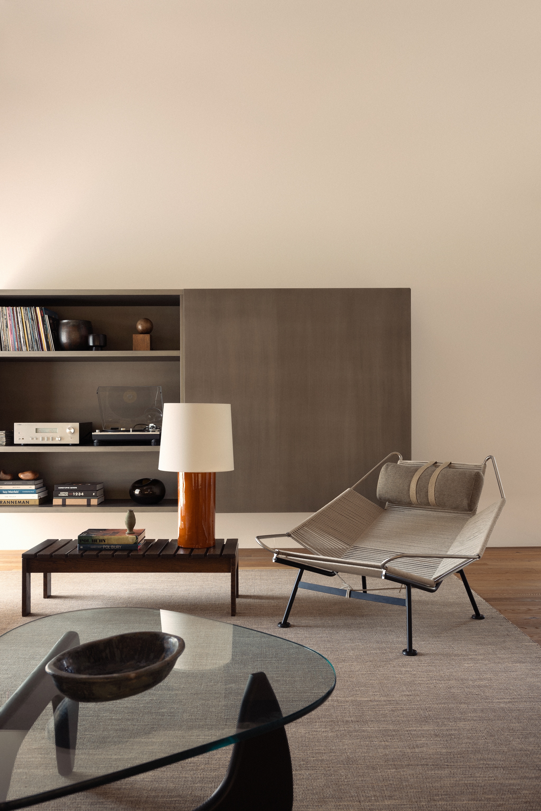 Zwevende kast en tafellamp Lisboa, ontworpen door Stef Claes. Bank Flexform via RR Interieur. Vintage tafels naast bank Poul Kjærholm. Kubuskunstwerk Pol Bury. Salontafel Isamu Noguchi, aardewerk erbovenop Pierre Culot. Vintage stoelen en houten tafel Martin Visser via Céline Hellin. Stalamp Santa & Cole. Fauteuil Flag Halyard van Hans J. Wegner voor Pp Møbler.