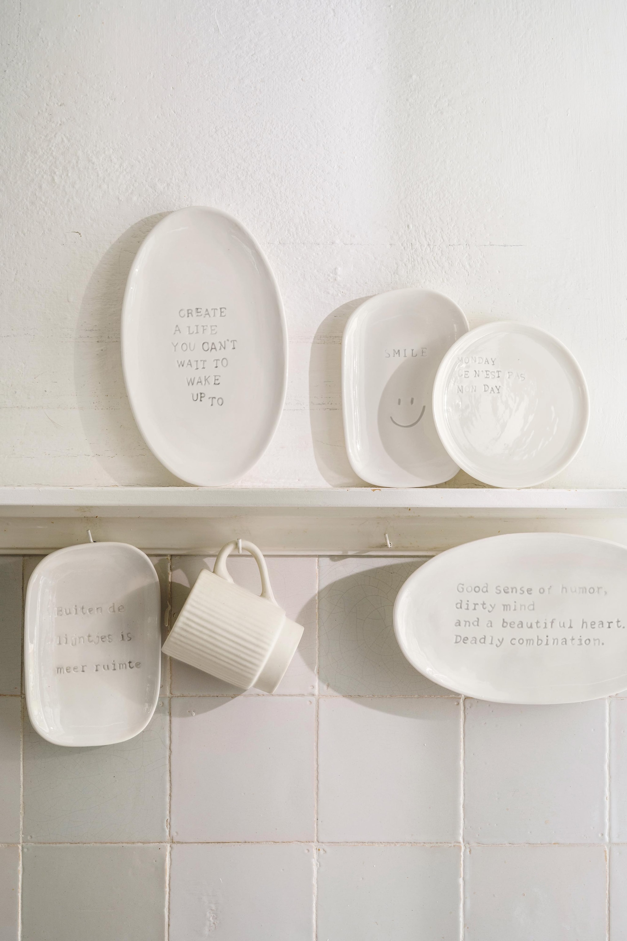 vtwonen muurdecoratie create, keramiek, gebroken wit, 15x1,5x25,5 cm (bxdxh) € 24,95, vtwonen muurdecoratie ruimte, monday en smiley,  keramiek, gebroken wit, ruimte en smiley 12x1,5x18 cm (bxdxh), monday 15,2x1,5 cm (Øxd), set van 3 € 39,-, vtwonen muurdecoratie humor, keramiek, gebroken wit, 25,5x1,5x15 cm (lbxdxh) € 24,95. vtwonen 04-2026 | styling Sanne Ketelaar | fotografie Stan Koolen