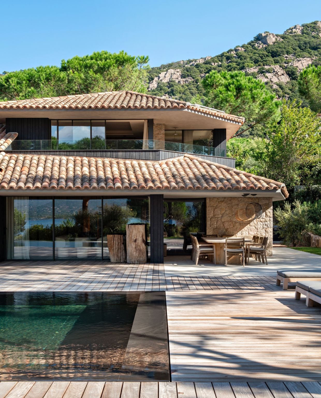 Houten tafel vintage. Houten stoelen Slots Décoration. Hanglampen Foscarini. Teakhouten ligbedden StudioPiet Boon. vtwonen Design 02-2026 | styling Laurence Dougier | fotografie Nicolas Mathéus | productie Living Inside