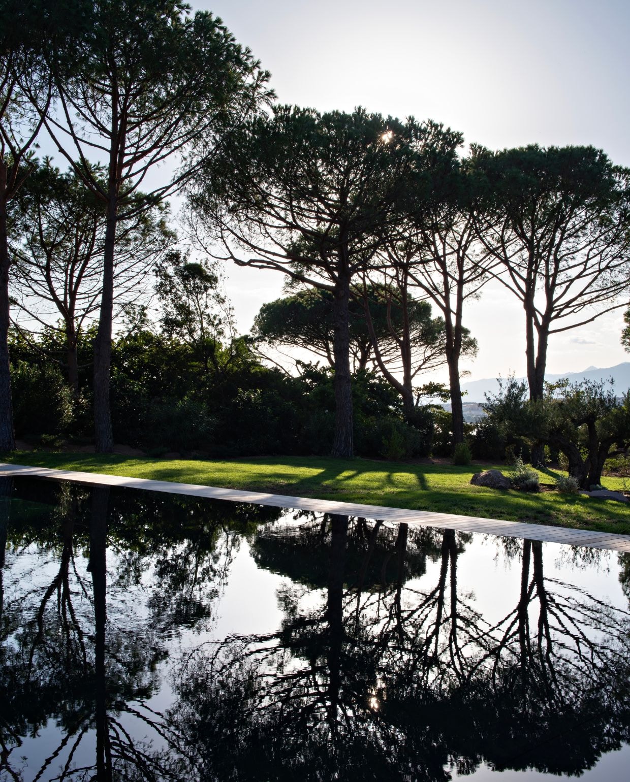 Binnen en buiten lopen naadloos in elkaar over. Met het zwembad van grijs lavasteen als middelpunt. vtwonen Design 02-2026 | styling Laurence Dougier | fotografie Nicolas Mathéus | productie Living Inside