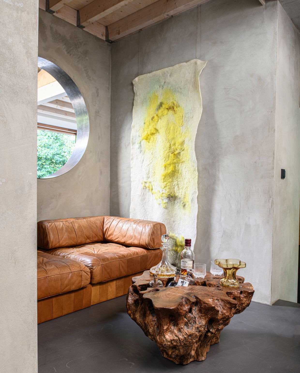 Wanden gestuct met betonmortel. Vintage bank De Sede. Salontafel Mija. Wandkleed Beatrice Waanders. vtwonen 03-2026 | styling Marit Saladini | fotografie Louis Lemaire