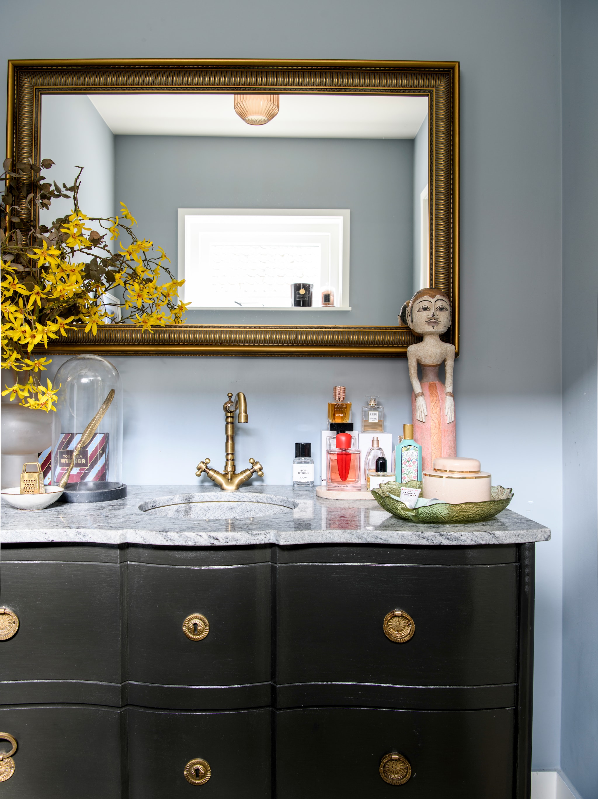 Badkamermeubel Maisons du Monde. Kraan Hudson Reed. Vintage spiegel en stolp uit Parijs. Beeld uit Indonesië. Parfum Skins Amsterdam. Muurkleur Parma Grey van Farrow & Ball. vtwonen 06-2026 | styling Esther Loonstijn | fotografie Louis Lemaire