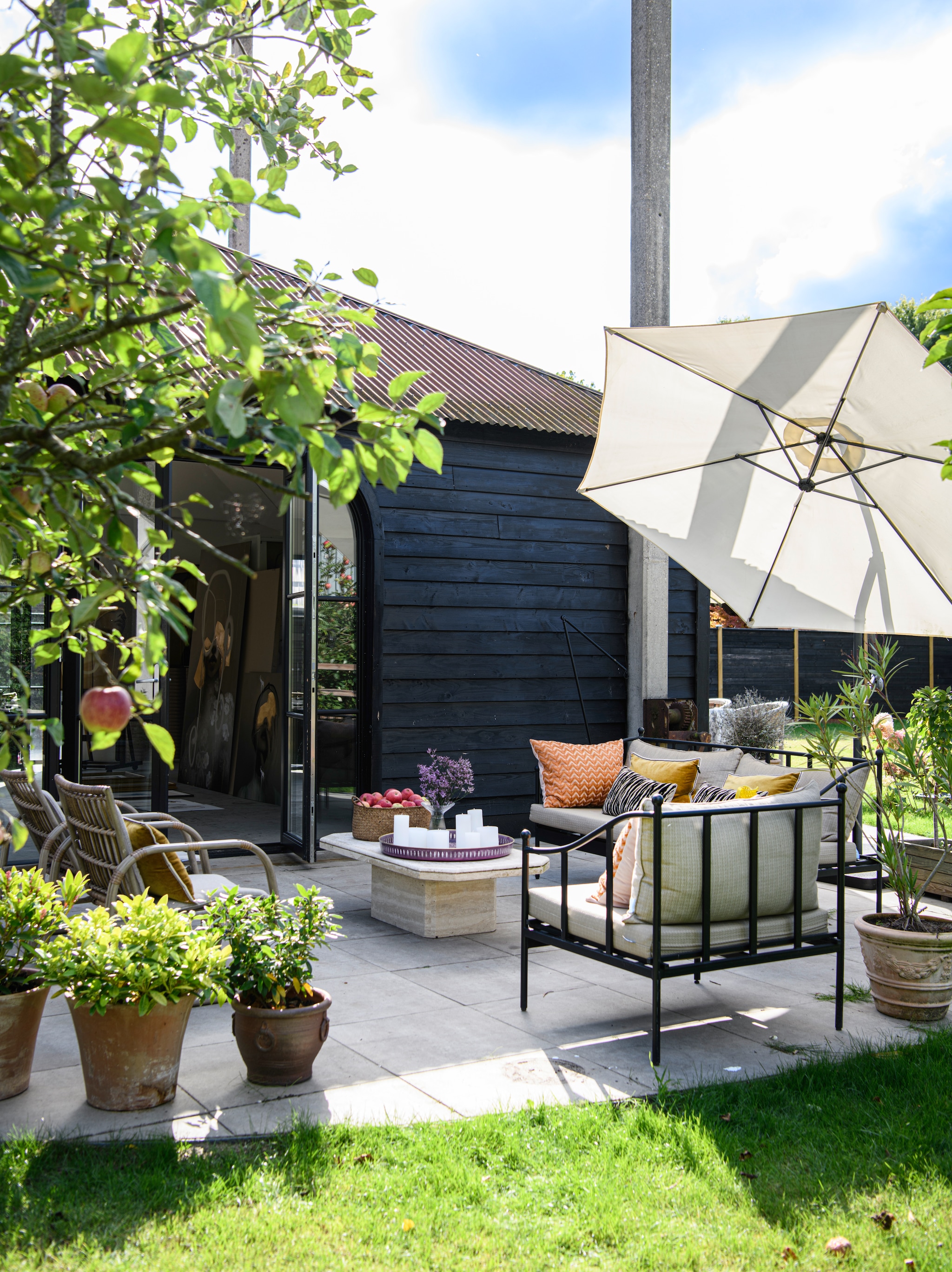 Banken Maisons du Monde. Kussens Élitis. Parasol Sklum. Stoelen Maisons du Monde. Tafel kringloop. Dienblad Van Verre. Mand Intratuin. Potten kringloop en Tuincentrum het Oosten. vtwonen 06-2026 | styling Esther Loonstijn | fotografie Louis Lemaire