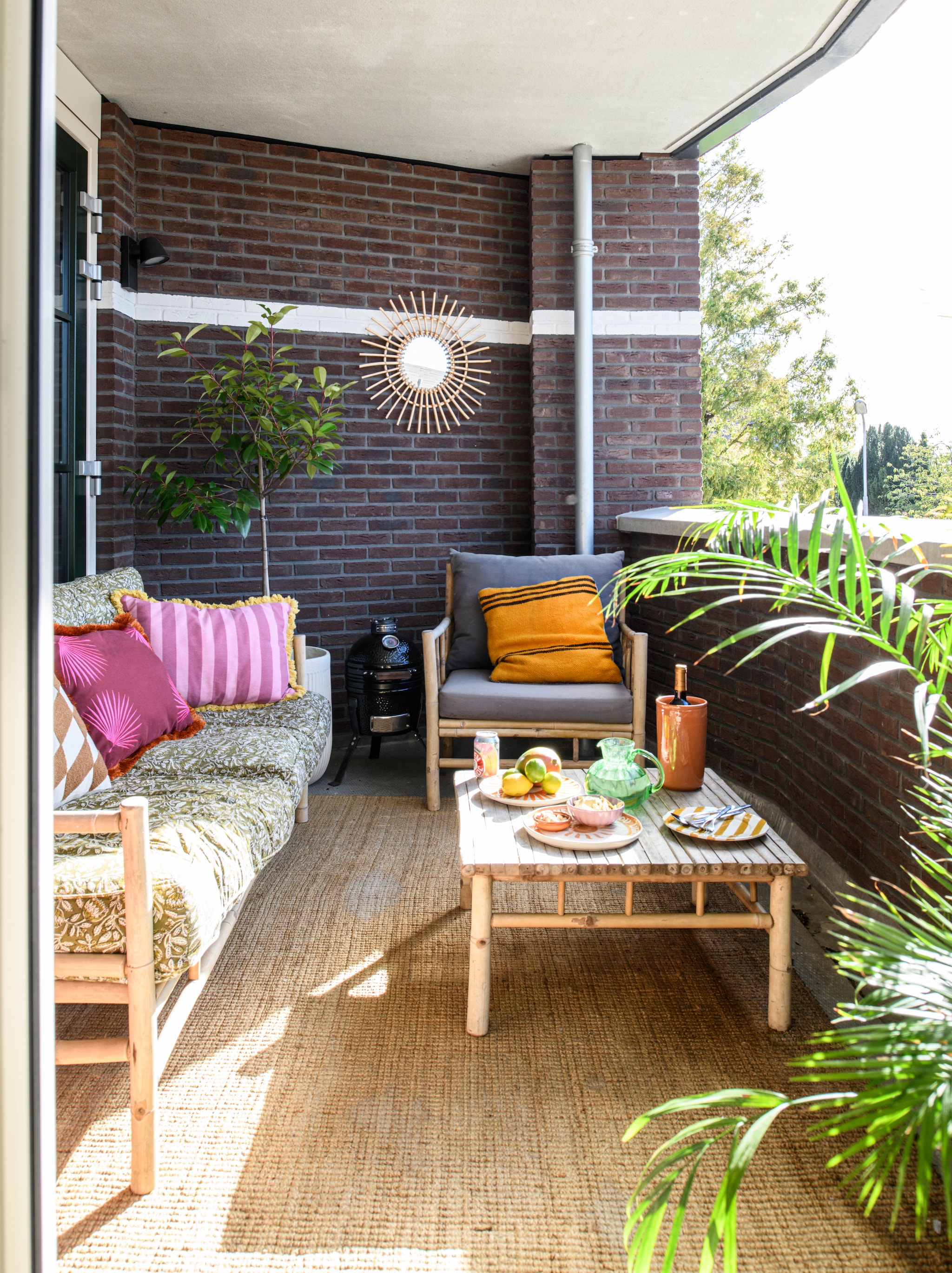 Bank, fauteuil, grijze kussens, vloerkleed en salontafel Marktplaats. Loungekussens De Eekhoorn. Oranje sierkussen, spiegel, karaf, borden en wijnkoeler kringloop. Overige kussens Loods5. vtwonen 06-2026 | styling Maaike van Haaster | fotografie Louis Lemaire | productie Insidehomepage