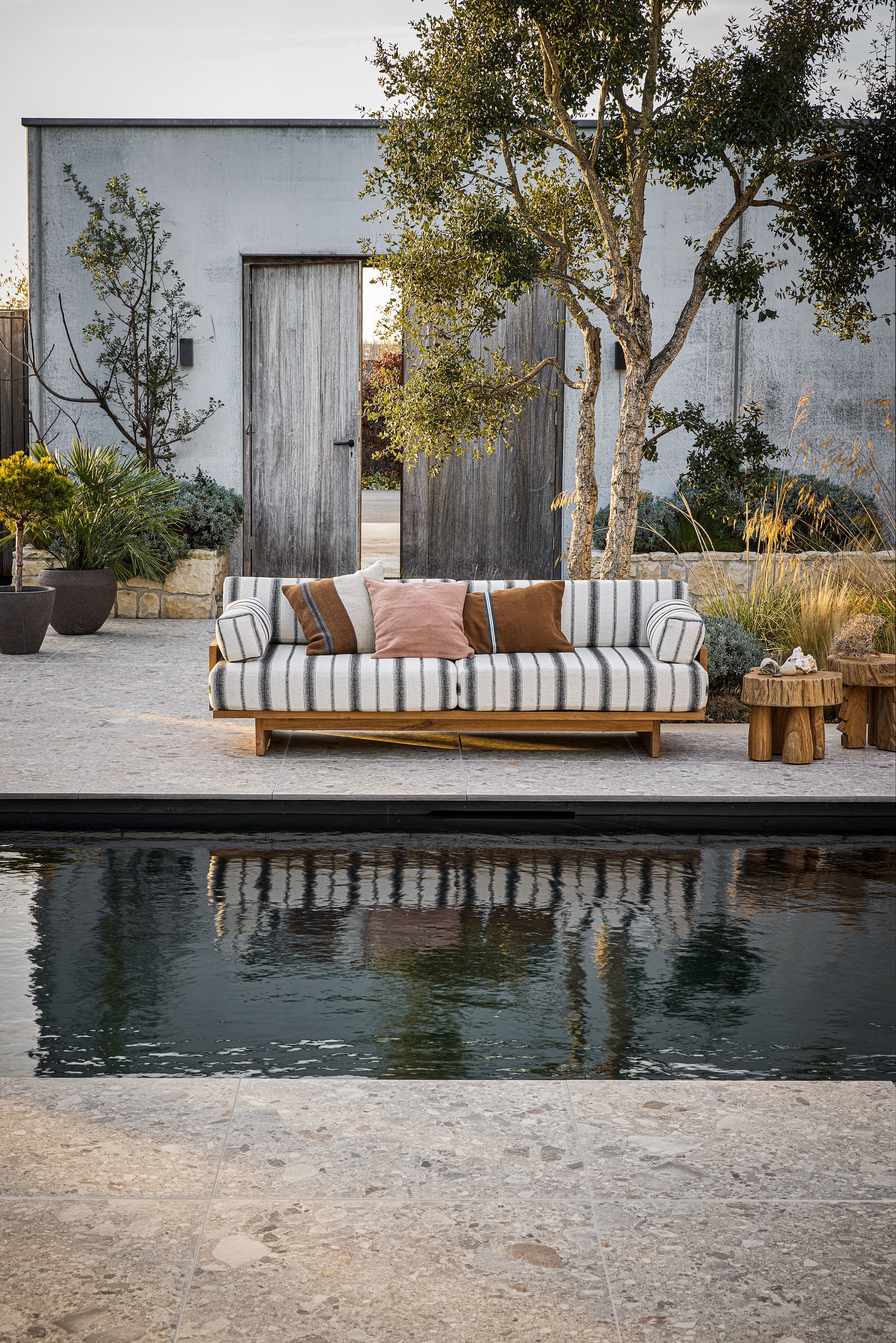 vtwonen tuintegel Composite Mix, keramiek, beige, 80x80 cm (lxb), per per m² € 76,-.M.m.v. hkliving.com (buitenbank, bijzettafels), libecohomestores.eu (kussens), studio-buiten-shop.nl (buitenpotten Atelier Vierkant). Overig privébezit. vtwonen 04-2026 | styling Kim van Rossenberg | fotografie Peggy Janssen