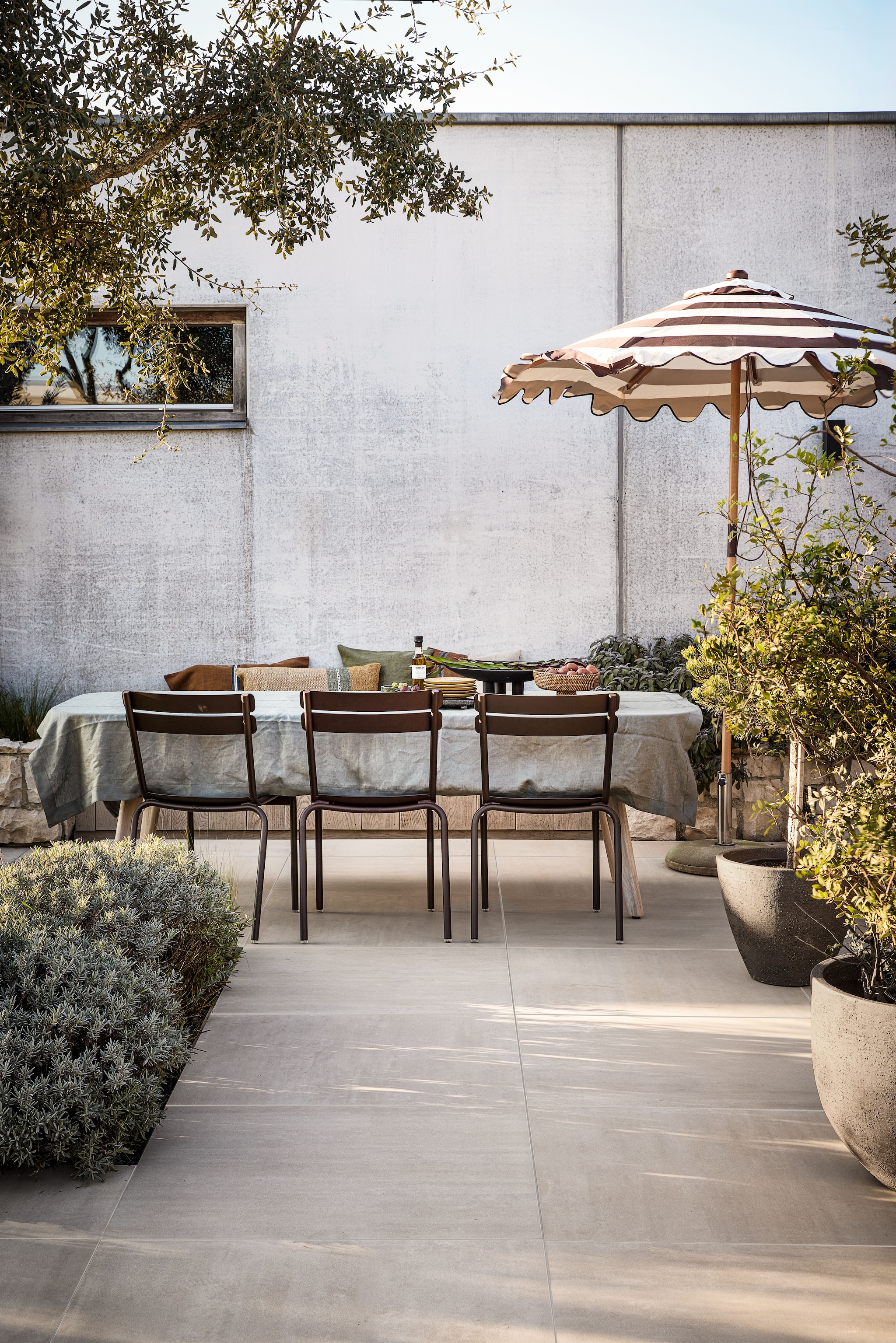 vtwonen tuintegel Form, keramiek, beige, 90x90 cm (lxb), per m² € 84,50.M.m.v. extravert.nl (stoelen), studio-buiten-shop.nl (buitenpotten), borek.eu (tafel), zarahome.com (tafelkleed), hkliving.com (parasol), libecohomestores.eu (kussens). Overig privébezit.