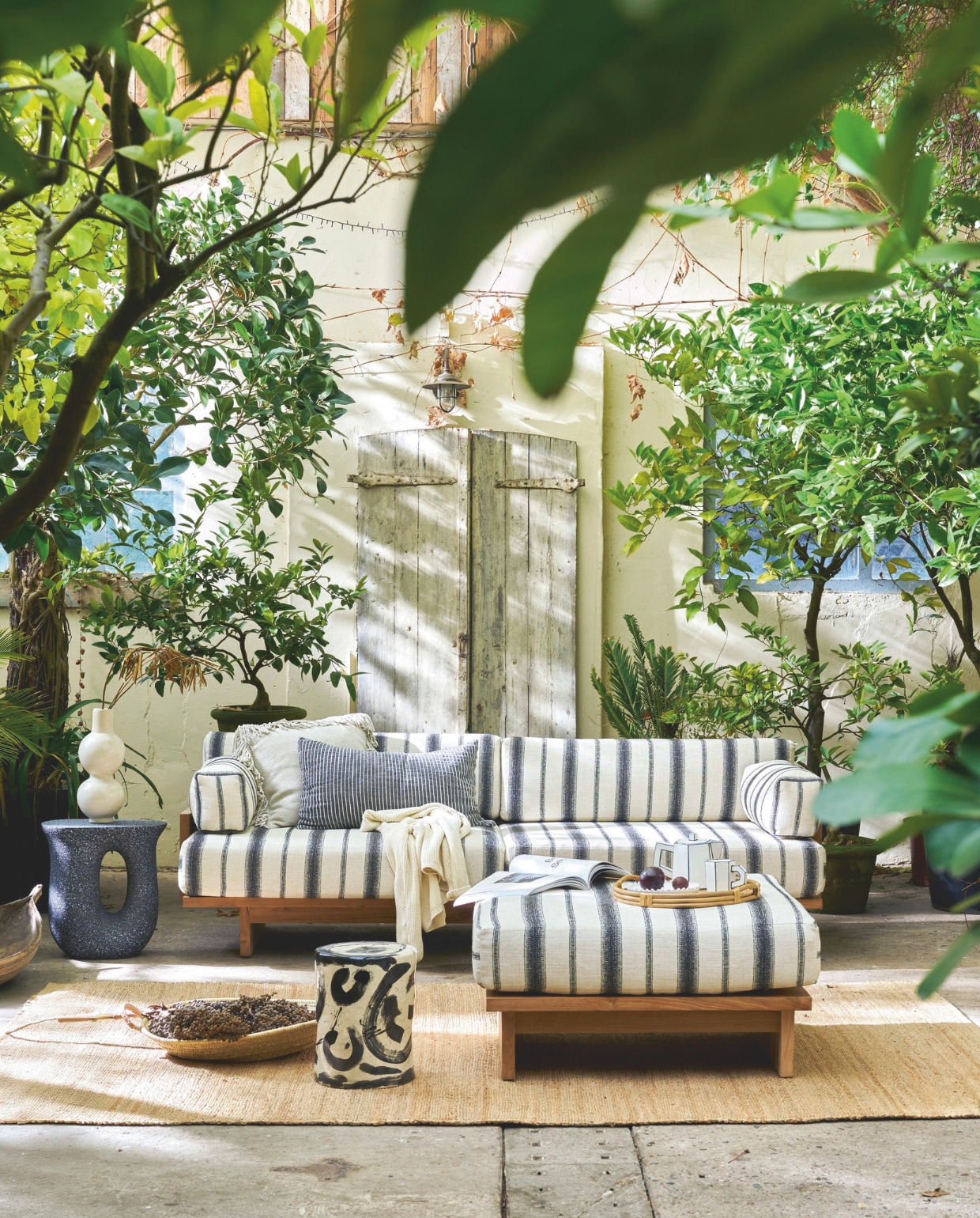 HKliving outdoor loungebank Chalkstripe, teak, 227x93,5x67 cm (bxdxh) € 3295,-, outdoor hocker Chalkstripe, teak, 88x88x38cm (bxdxh) € 995,-, vloerkleed, jute naturel, 340x240 cm (lxb) € 329,-, kussen Monochrome, linnen/katoen, gestreept zwart-wit € 54,90, Household Hardware platte mand Marrakech, riet, L € 65,-, vaas Bubble, tadelakt € 115,-, Woood bijzettafel Mason, magnesium, zwart gespikkeld, 42x33x45 cm (lxbxh) € 99,95 (shop.vtwonen.nl). Omar buitenkussen Oat, met franjes, beige, inclusief vulling € 210,- (omar-antwerp.be). Serax bijzettafel 06 Sophia Pawn, keramiek, zwart-wit, 27x34 cm (Øxh) € 190,-, theepot Carte Blanche, porselein € 45,-, beker Carte Blanche, porselein € 22,- (serax.com). Zara Home dienblad, rotan € 49,99 (zarahome.com). Overig privébezit. vtwonen 03-2026 | styling Cleo Scheulderman | fotografie Jeroen van der Spek