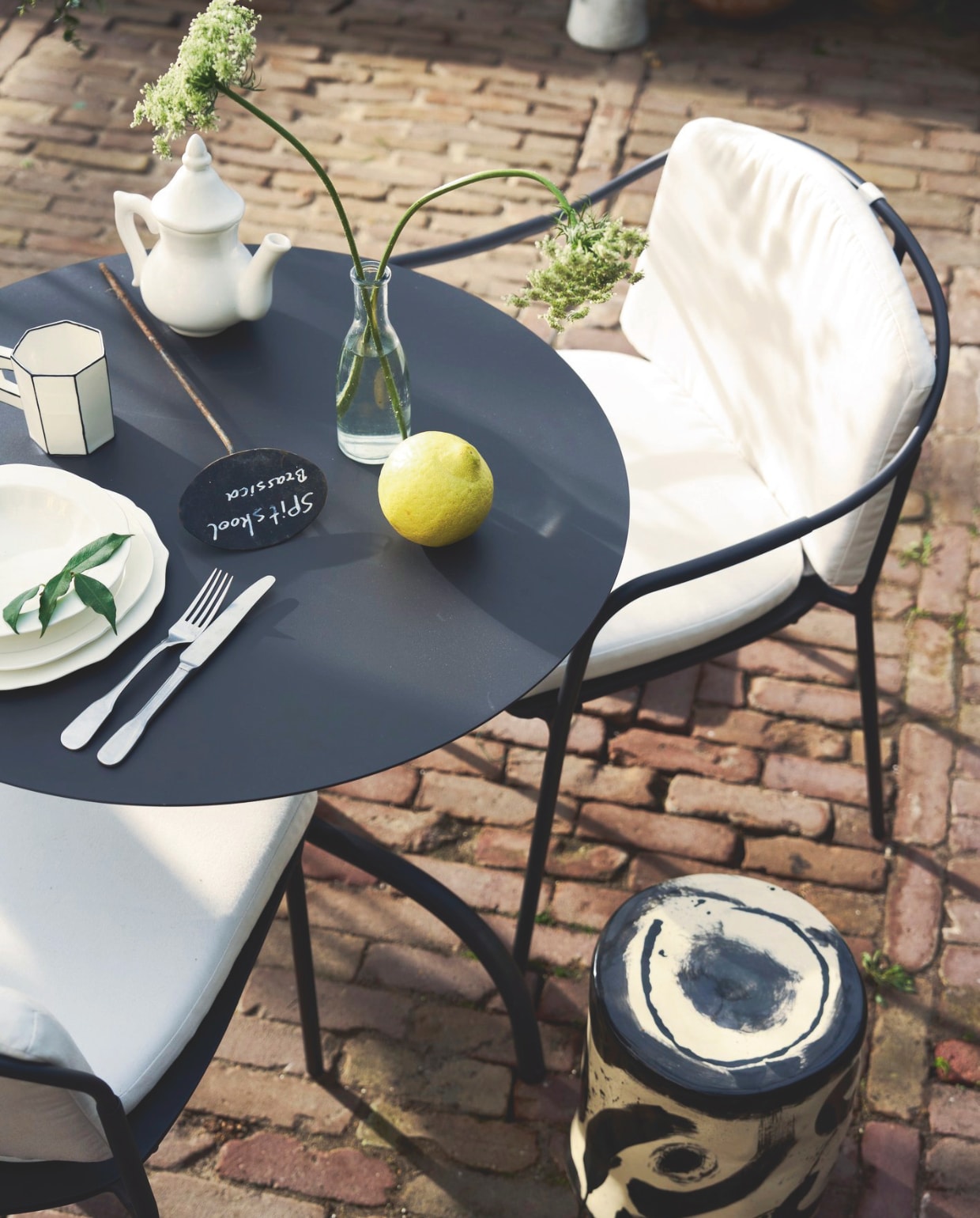 Serax stoel Patio, aluminium, zwart € 370,-, stoel Patio met armleuningen, aluminium, zwart € 390,-, stoelkussen Patio € 100,-, tafel Patio, aluminium, zwart, 75x73 cm (Øxh) € 395,-, borden Silhouette, porselein, wit, vanaf € 8,50, bijzettafel 06 Sophia Pawn, keramiek, zwart-wit, 27x34 cm (Øxh) € 190,-, beker Carte Blanche, porselein € 22,- (serax.com). Household Hardware theepot € 49,- (householdhardware.nl). Kn Industrie bestek Brick Lane, rvs, met lepel € 7,-, vork € 7,- en  mes € 12,- (bymolle.com). Overig privébezit. vtwonen 03-2026 | styling Cleo Scheulderman | fotografie Jeroen van der Spek