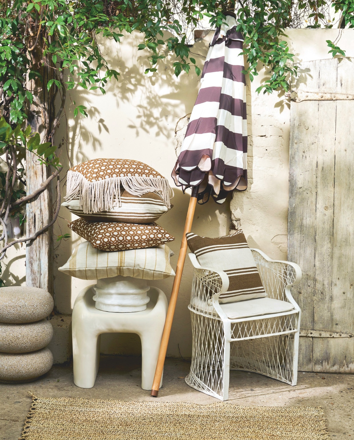 Household Hardware stoel Vanessa, polyester, 57x57x55cm (bxdxh) € 429,-, vloerkleed, gevlochten palmblad, prijs op aanvraag (householdhardware.com). Woood kruk Nivo, vezelversterkt polymeer, 52x50x51 (bxdxh) € 329,-, HKliving parasol Striped Patio, polyester en teakhout, stracciatella, 270 cm (Ø) € 695,-, Woood bijzettafel Laurel, magnesium, spikkels beige, 40x50 cm (Øxh) € 99,95 (shop.vtwonen.nl). Omar buitenkussen Oxy, fijn gestreept, crème-lichtbruin, inclusief vulling€ 195,-, buitenkussens Odile, patroon, amandel, inclusief vulling€ 145,-, en buitenkussens Odile met franjes, patroon, inclusief vulling€ 165,-, buitenkussens Olga, breed gestreept, crème-bruin, inclusief vulling € 125,- (omar-antwerp.be). Serax plantenpot Earth, papier-maché, wit € 185,- (serax.com). vtwonen 03-2026 | styling Cleo Scheulderman | fotografie Jeroen van der Spek