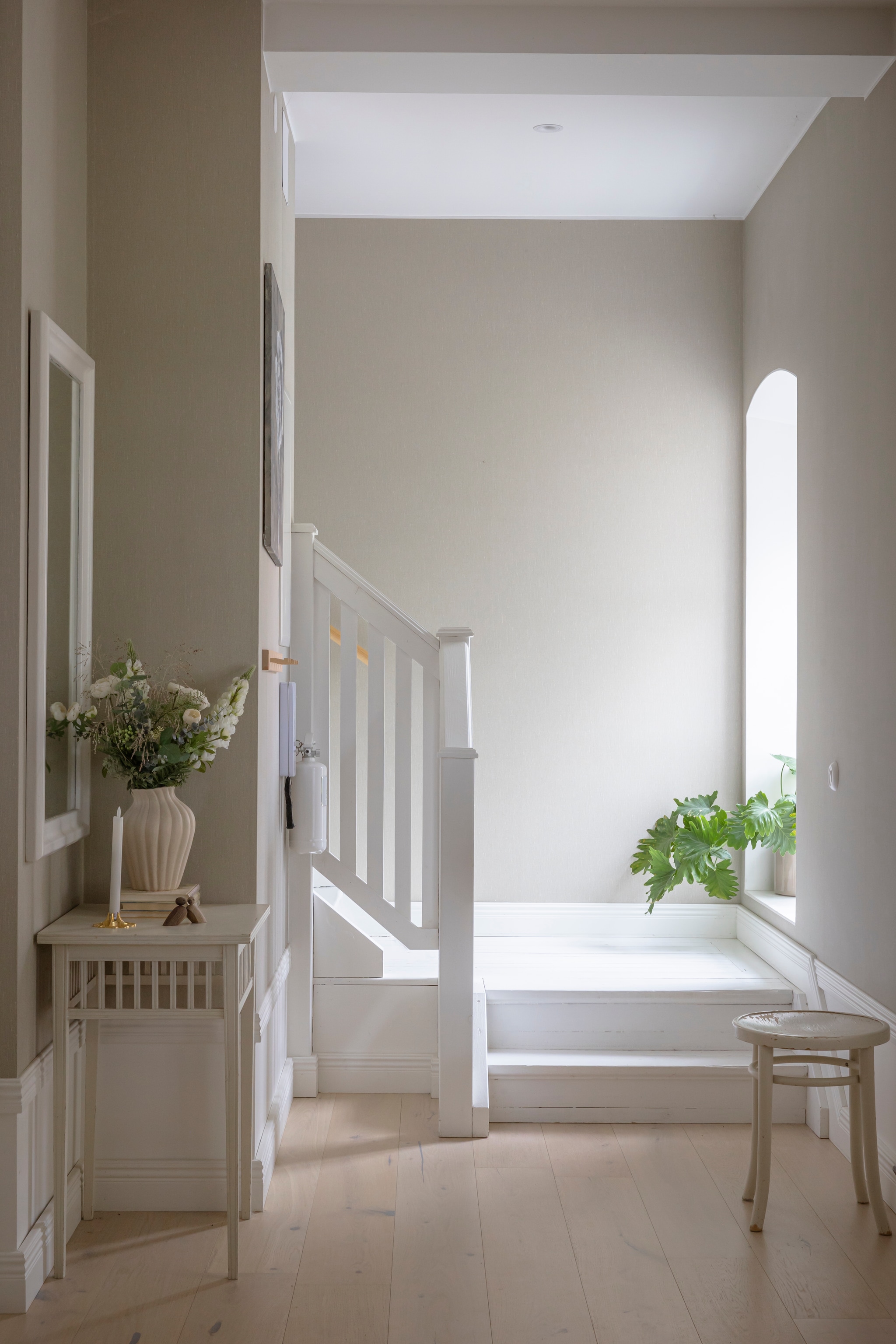 Behang Linen Beige 4315 van Boråstapeter. Vloer gewit eiken van Bjelin. Spiegel erfstuk. Bijzettafel en kruk vlooienmarkt. Vaas Indiska. Kandelaar Skultuna. vtwonen Landelijk 06-2026 | styling Anna Bjelkholm | fotografie Anna Karlsson