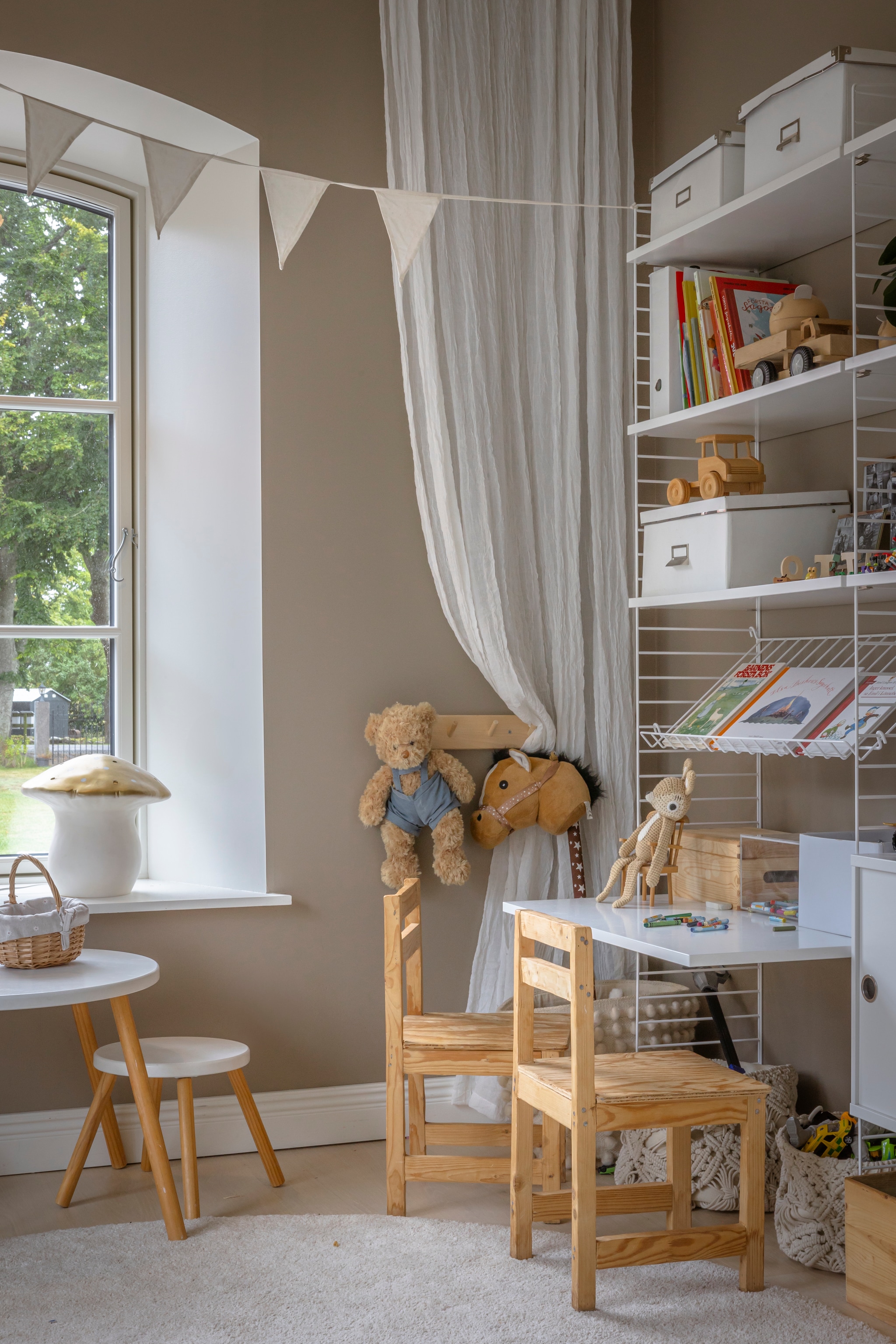 3 Muurverf kleur Muskatnøtt van Jotun. Vloer gewit eiken van Bjelin. Vloerkleed en dozen Ikea. Gordijnen Jotex. Vlaggenlijn Jabadabado. Paddenstoellamp Heico. Tafel en stoel Jollyroom. Stoel en kruk vlooienmarkt. Mand H&m. vtwonen Landelijk 06-2026 | styling Anna Bjelkholm | fotografie Anna Karlsson