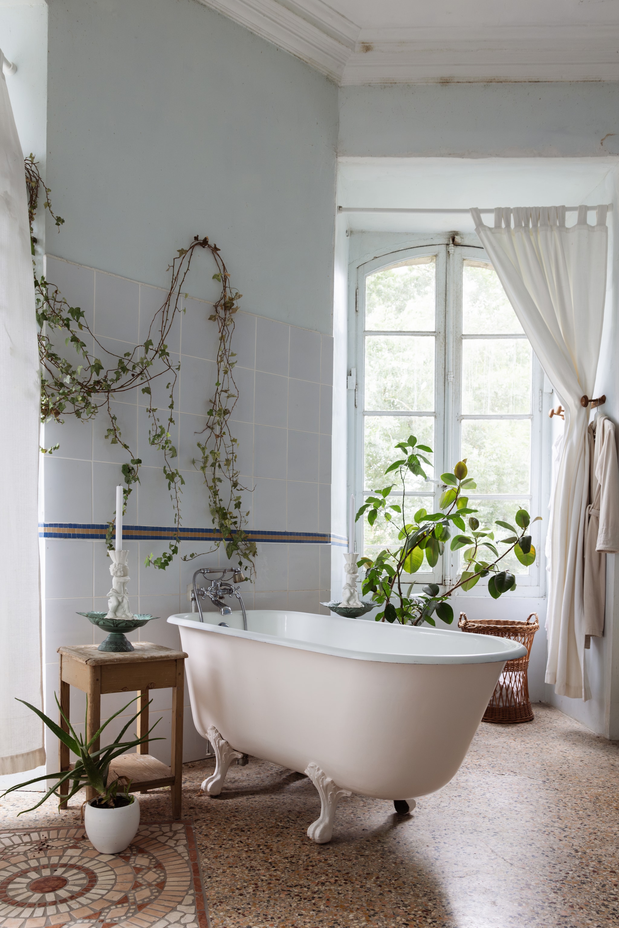 Bijzettafel, kandelaar en mand brocante. Linnen gordijn La Redoute. Badjas De Bijenkorf. Planten Intratuin. vtwonen Landelijk 06-2026 | styling Ilona Jongepier | fotografie Dana van Leeuwen