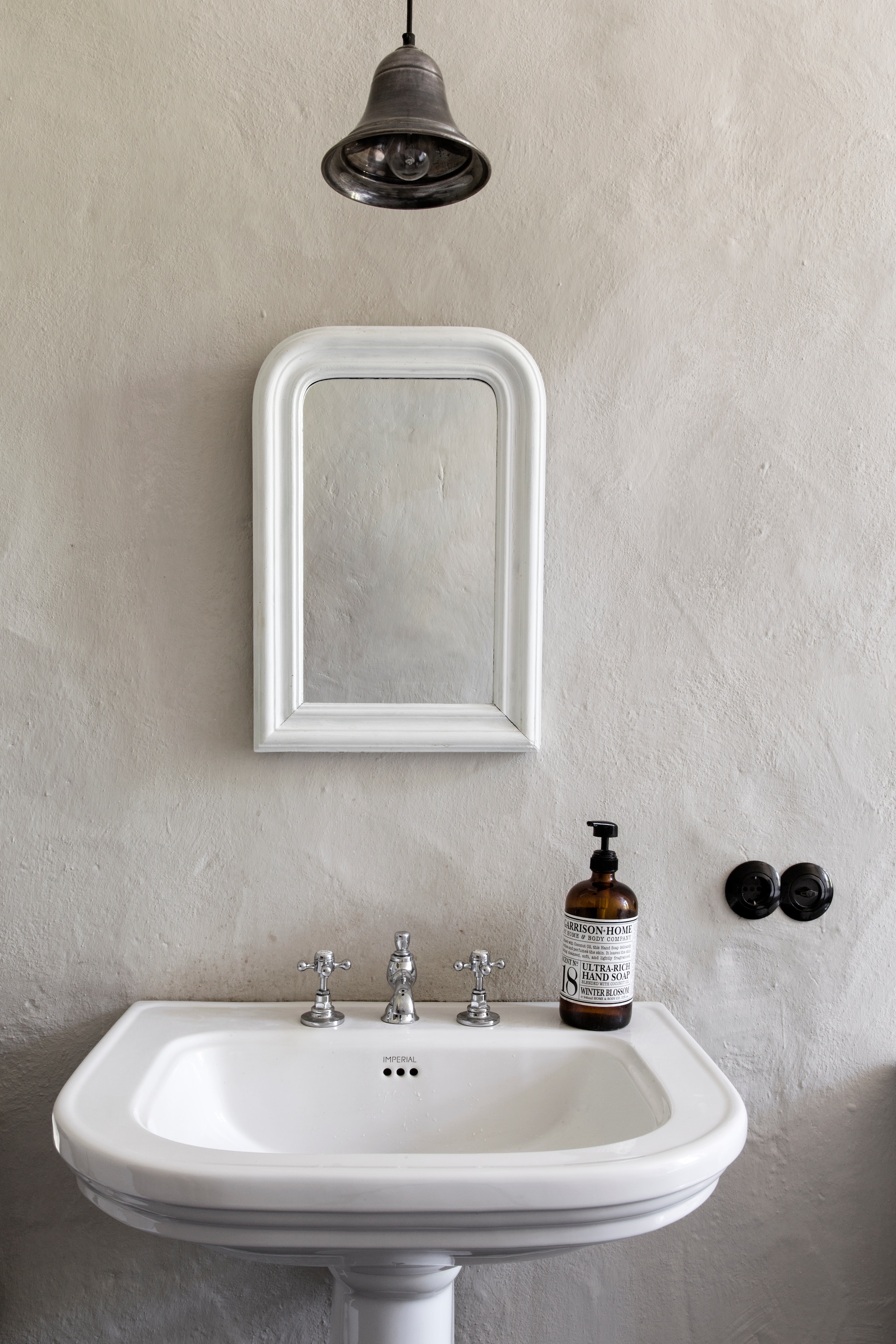 Wasbak Imperial Bathrooms. Lamp Loberon. Spiegel antiek, wit geschilderd door Volker. Op de muur kalkverf, zelf gemengd met ecologisch pigment, beide Kreidezeit. vtwonen Landelijk 06-2026 | Styling Miriam Hannemann | Fotografie André Reuter