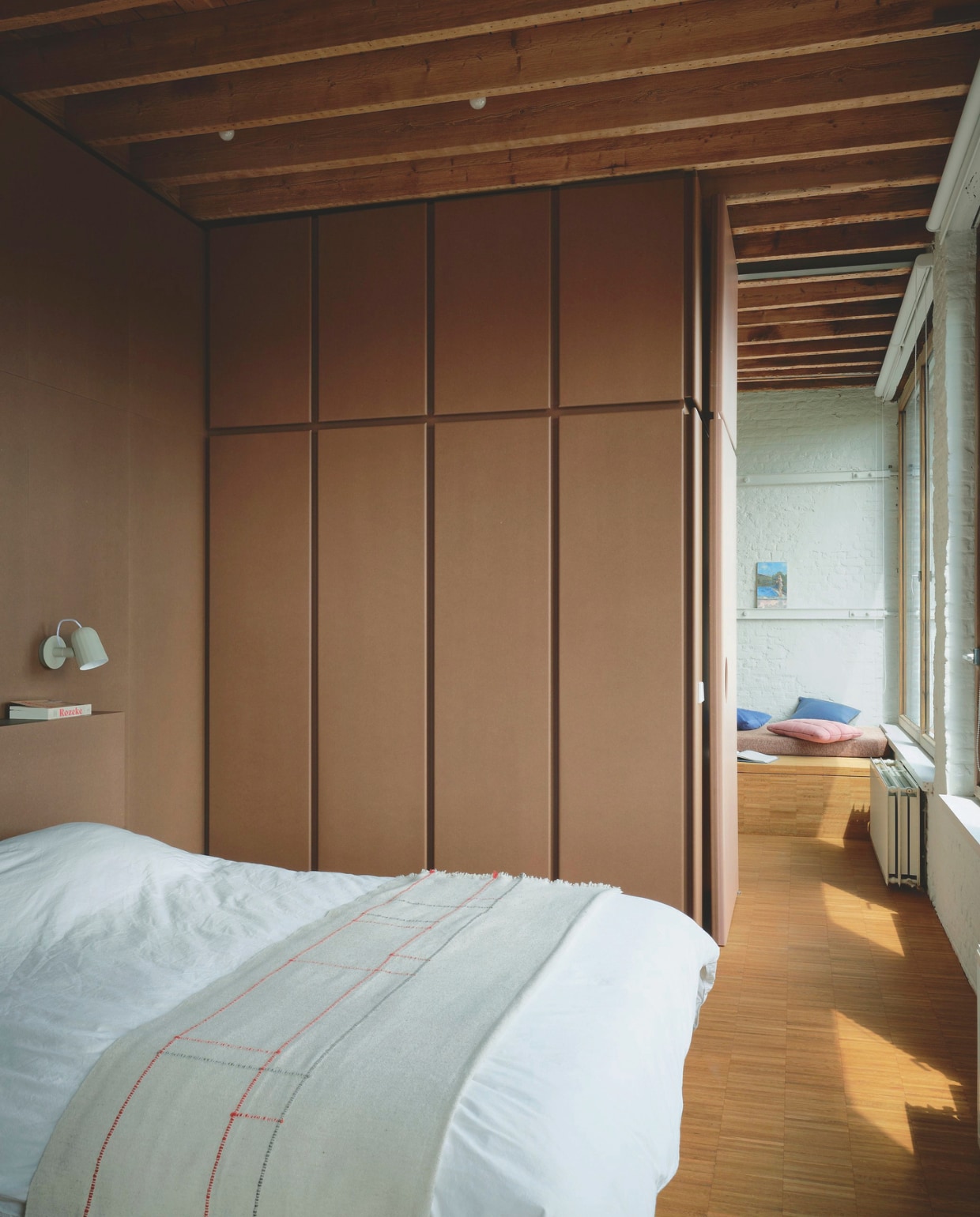 Bed en inbouwkast maatwerk door Decor Finesse, naar een ontwerp van B-bis Architecten. Plaid Marie-Marie. Leeslampen Hay. Daybed bij het raam ontworpen door Roos Mertens. vtwonen design 02-2026 | Fotografie Mr. Frank