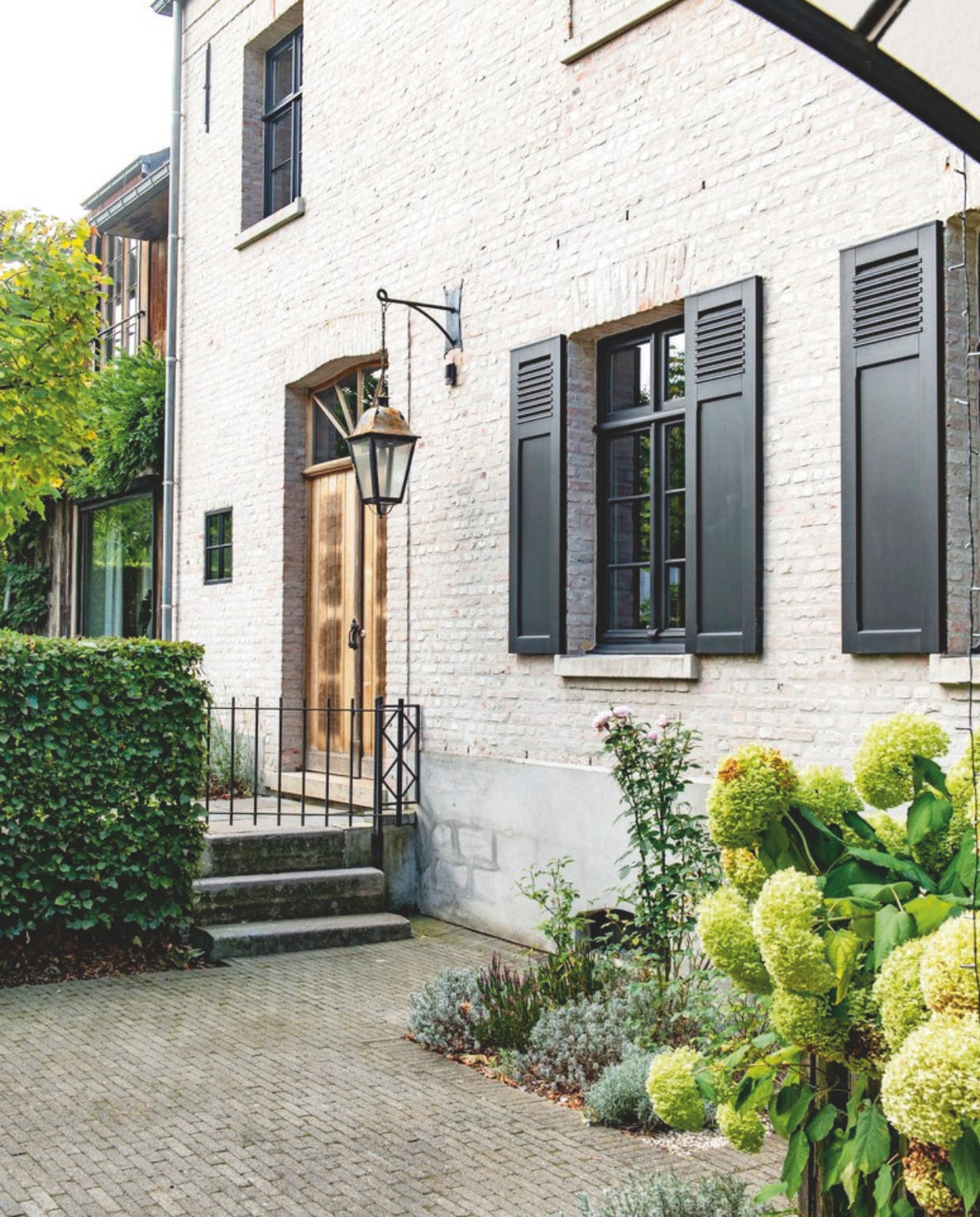 Verfkleur kozijnen Gitzwart, gemengd bij Colora. Hegsoort beukenhaag. Planten in border sneeuwbalhortensia ‘Annabelle’, lavendel en rozen. vtwonen landelijk 03-2026 | styling Katleen Willaert | fotografie Caroline Coehorst