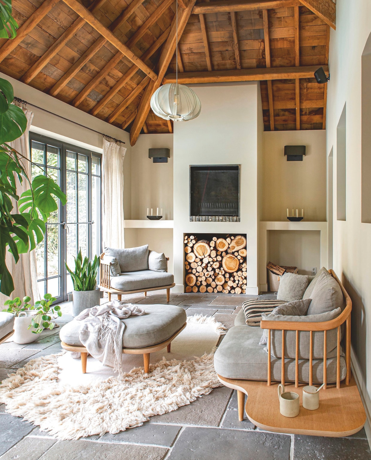 Muurkleur Buttercream Beige en kozijnenkleur Gitzwart, gemengd bij Colora. Gordijnen Puur Lifestyle. Tegelvloer Castle Stones. Kleed, sprei, kleine bloempot, bekers en kaarsenstandaards Ferm Living. Hanglamp Bolia. Bank, stoel en hocker &Tradition. Plantsoorten Monstera, Pilea peperomioides en Sansevieria trifasciata ‘Moonshine’. Grote bloempot Serax. vtwonen landelijk 03-2026 | styling Katleen Willaert | fotografie Caroline Coehorst