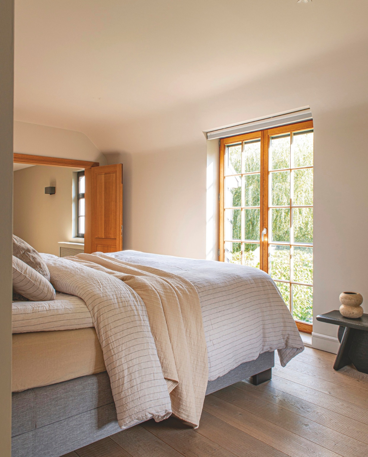 Muurkleur Skimming Stone en kozijnkleur Gitzwart, gemengd bij Colora. Bedden-goed Bonsoirs. Bed Sleeplife. Lampen &Tradition. Nachtkast Hübsch. Bijzettafel en vaas Zara Home. Wandkleed Ferm Living. vtwonen landelijk 03-2026 | styling Katleen Willaert | fotografie Caroline Coehorst