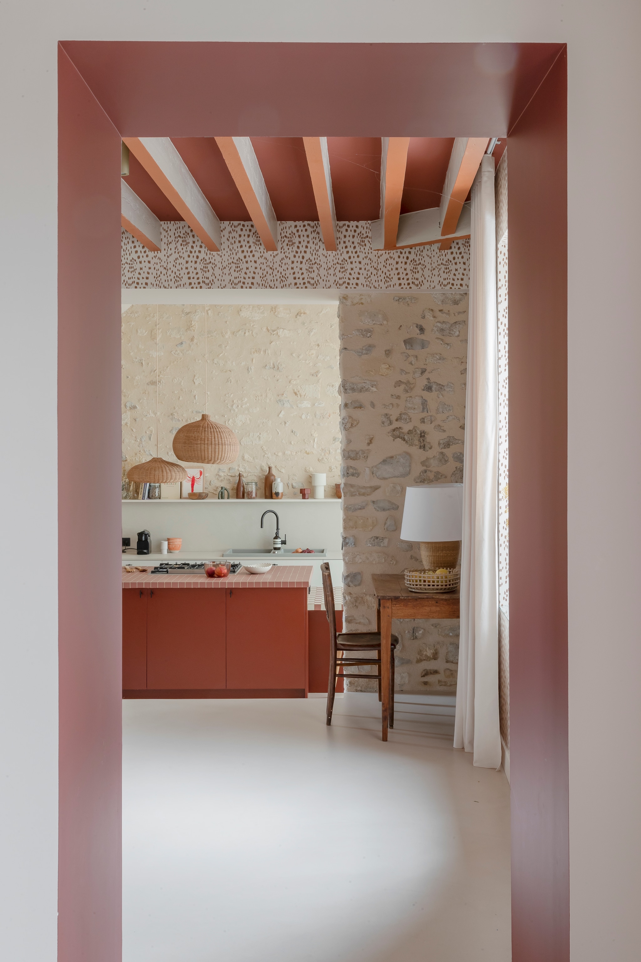 Keuken Snaidero. Eiland Valdesign. Kastdeurgreepjes Dauby. Beton ciré-vloer Ad Lucem. Gootsteen Blanco. Tegels Winckelmans. Hanglampen en tafellamp Ferm Living. Behang Les Touches van Brunschwig & Fils. Tafel en stoel vintage.