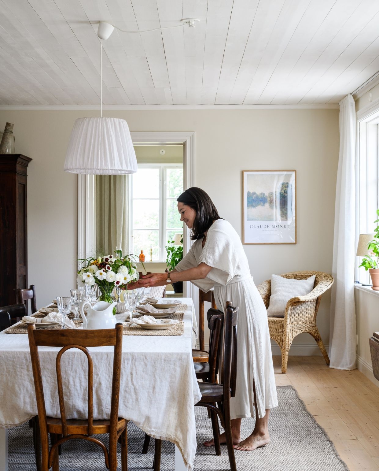 Stoelen Dakabom, tweedehands. Bloemen uit de tuin: dahlia, siergras, cosmos, Ammi majus, zonnehoed en zinnia. Tafelkleed Åhléns. Servetten H&m Home. Placemats Ellos. Glaswerk, borden, karaf, vaas en rotan stoelen tweedehands. Kast lokale antiekhandelaar. vtwonen Landelijk 03-2026 | fotografie Rebecca Martyn