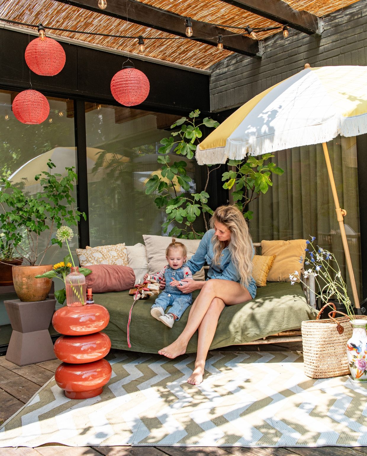 Priklampen Prikkabelled. Rode lantaarns Ikea. Bijzettafel Goossens. Grijze bijzettafel Kwantum. Buitenkleed en soortgelijke bank Wehkamp. Grote vaas Action. Kleine vaas Hema. Parasol Action. Kussens Karwei. Oranje bloempot Hornbach. vtwonen 03-2026 | fotografie Caroline Coehorst