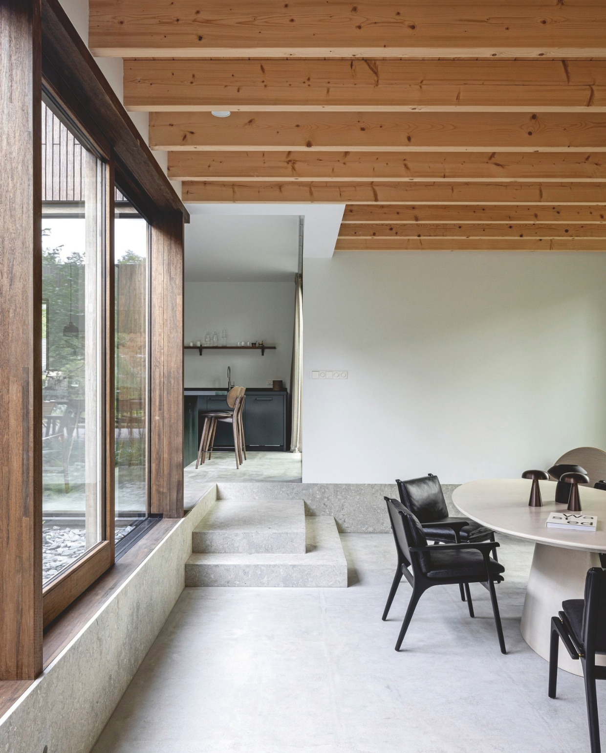 Stoelen Rén Dining Armchair van Stellar Works in eiken/zwart. Tafel Purdey D Design. Tafellampen &Tradition. Keukenstoelen Mater Design High Stool Backrest 69. De vloer is gemaakt van gevlinderd cement, de traptreden van Grigio Alpi-kalksteen.