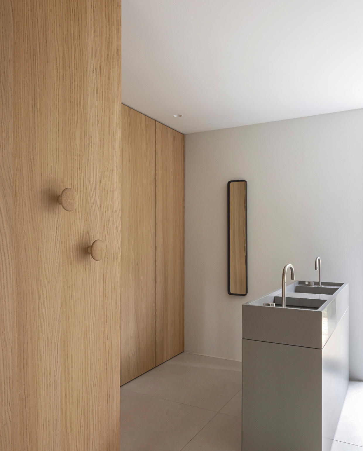 Wastafelmeubel en kraan Cocoon. Wandknoppen Muuto. Spiegel merkloos. Vloertegels Blend Chalk White van Piet Boon. vtwonen design 02-2026 | fotografie Tim Van de Velde