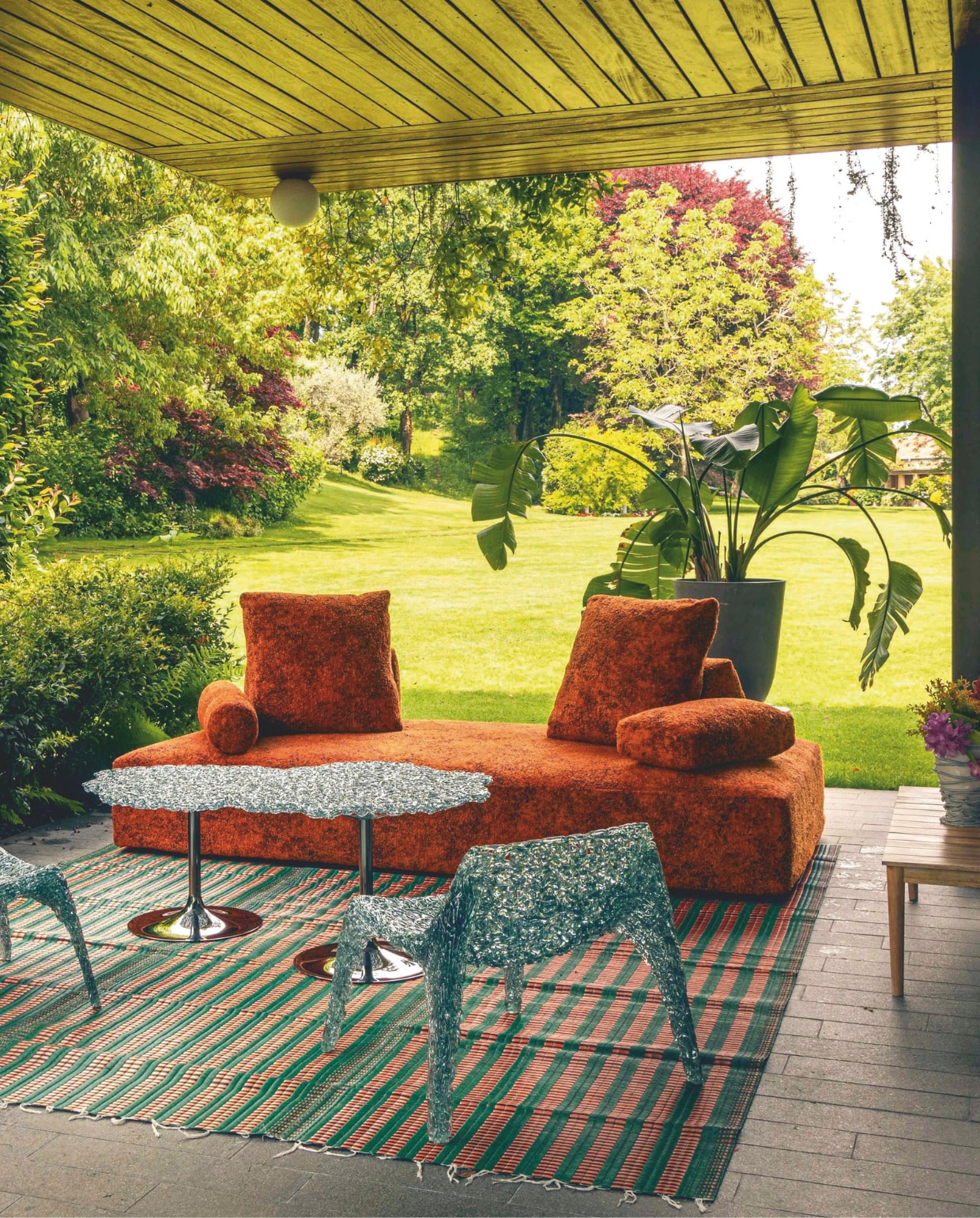 Eilandbank Sherazade Outdoor, bekleed met Every Stone Imperial Red, bijzettafel Diamante en loungestoelen Veronica Poltrona van Edra. Afrikaans vloerkleed handgemaakt van plastic afval. Vaas ontwerp van Gaetano Pesce. vtwonen design 02-2026 | fotografie Mattia Aquila