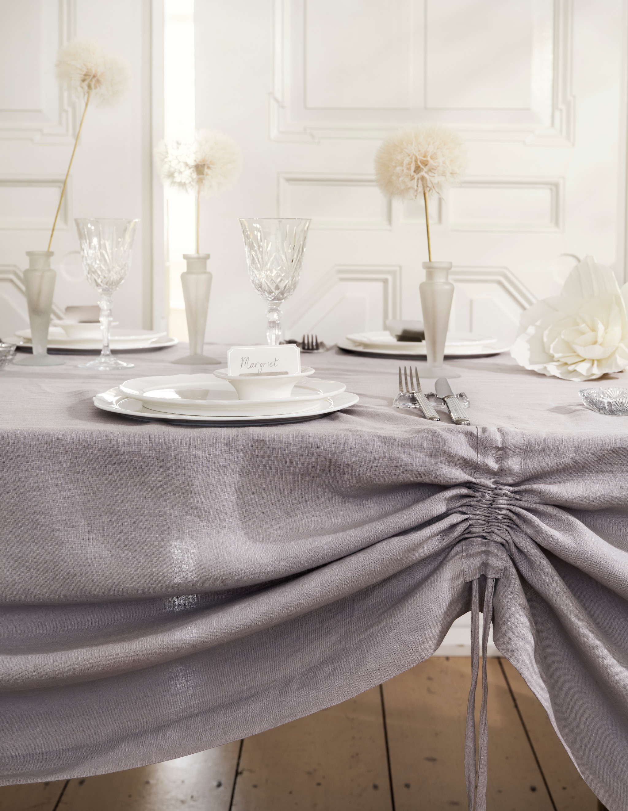 Zara Home gegraveerde wijnglazen, kristallook € 7,99, vier-delige bestekset, staal € 35,99, kandelaar Colin King (als vaas), matglas € 29,99, naamkaarthouders en kaartjes, metaal en papier, set van 8 houders en 24 kaartjes € 15,99 (zarahome.com). Schaaltje, glas (kringloopwinkel). Oury Home handgemaakt tafelkleed, linnen, lila, 320x200 cm (lxb) € 325,- (ouryhome.com). Serax serviesgoed, collectie Silhouette Dinnerware, porselein, wit, vanaf € 5,- (serax.com). Droogbloemen Kwekerij geprepareerde pluizenbollen € 17,95 (droogbloemenkwekerij.nl). Slinger Shop decoratiebloemen, papier, pretty powder, set van 3 € 8,99 (slingershop.nl). vtwonen Landelijk 06-2026 | styling Kim van Rossenberg | fotografie Stan Koolen
