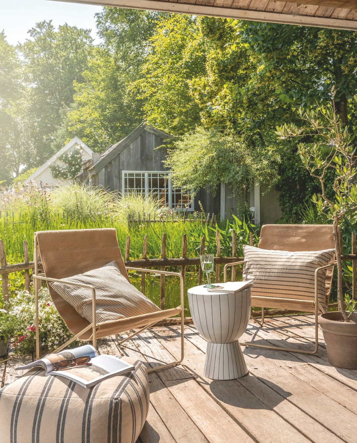 vtwonen poef, katoen en linnen, beige en grijs, 45x45x25cm (lxbxh) € 69,95, vtwonen sierkussen vierkant, katoen en linnen, beige en donkerblauw, 50x50 cm (lxb) € 44,95, vtwonen sierkussen rechthoek, katoen en linnen, beige en donkerblauw, 70x50 cm (lxb) € 59,95, vtwonen wijnglas, gerecycled glas € 14,95,vtwonen bijzettafel, metaal, wit en donkerblauw, 35,5x46 cm (Øxh) € 169,-,M.m.v. fermliving.com (fauteuil), shop.vtwonen.nl (mok met oor van vtwonen). Overig privébezit. vtwonen landelijk 03-2025 | styling Sanne Ketelaar | fotografie Stan Koolen